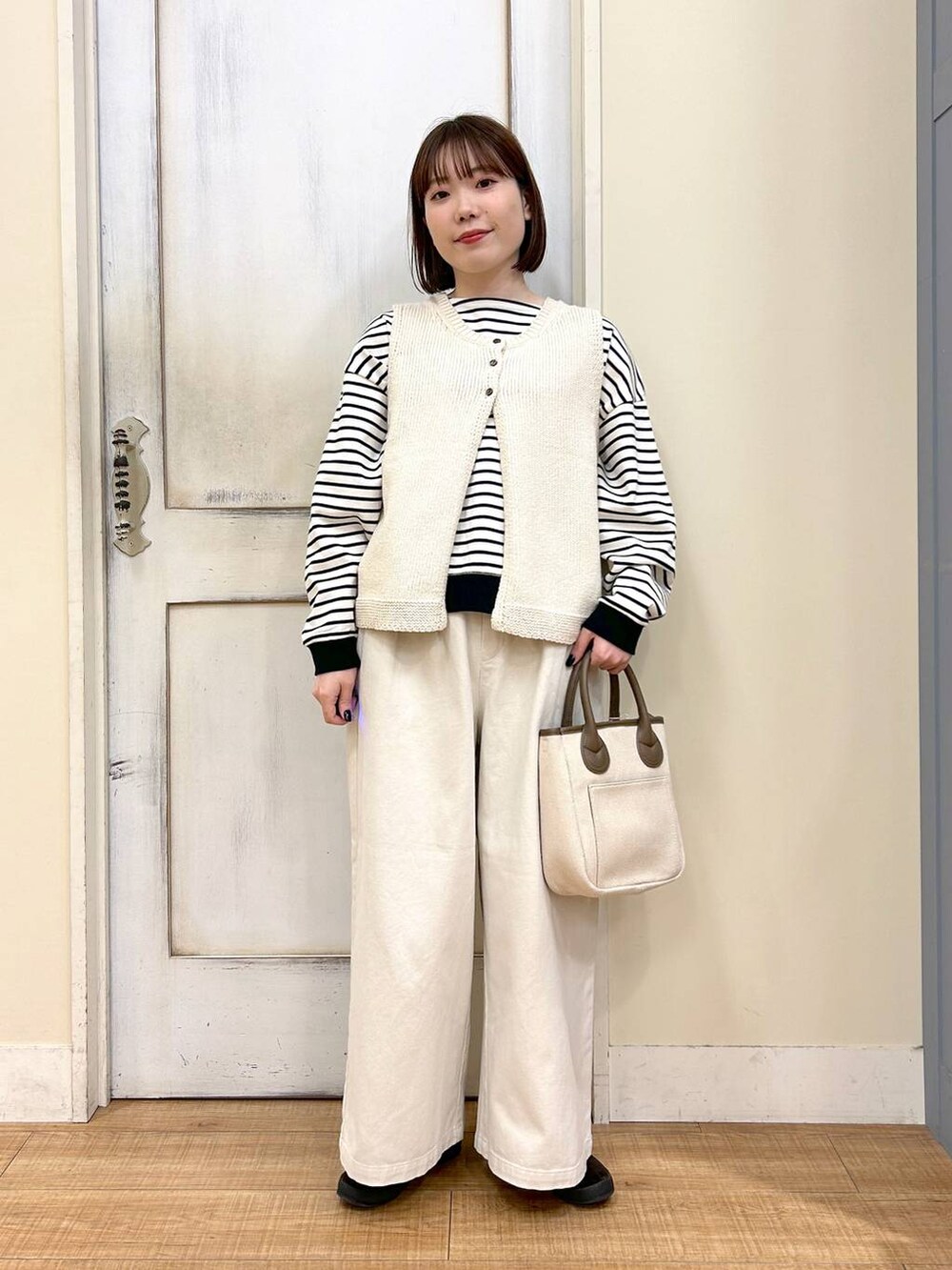 ホワイト系のトートバッグ、ブラウン系のスニーカー、ベージュ系のその他パンツを着用したレディースの春コーディネートの2枚目の写真