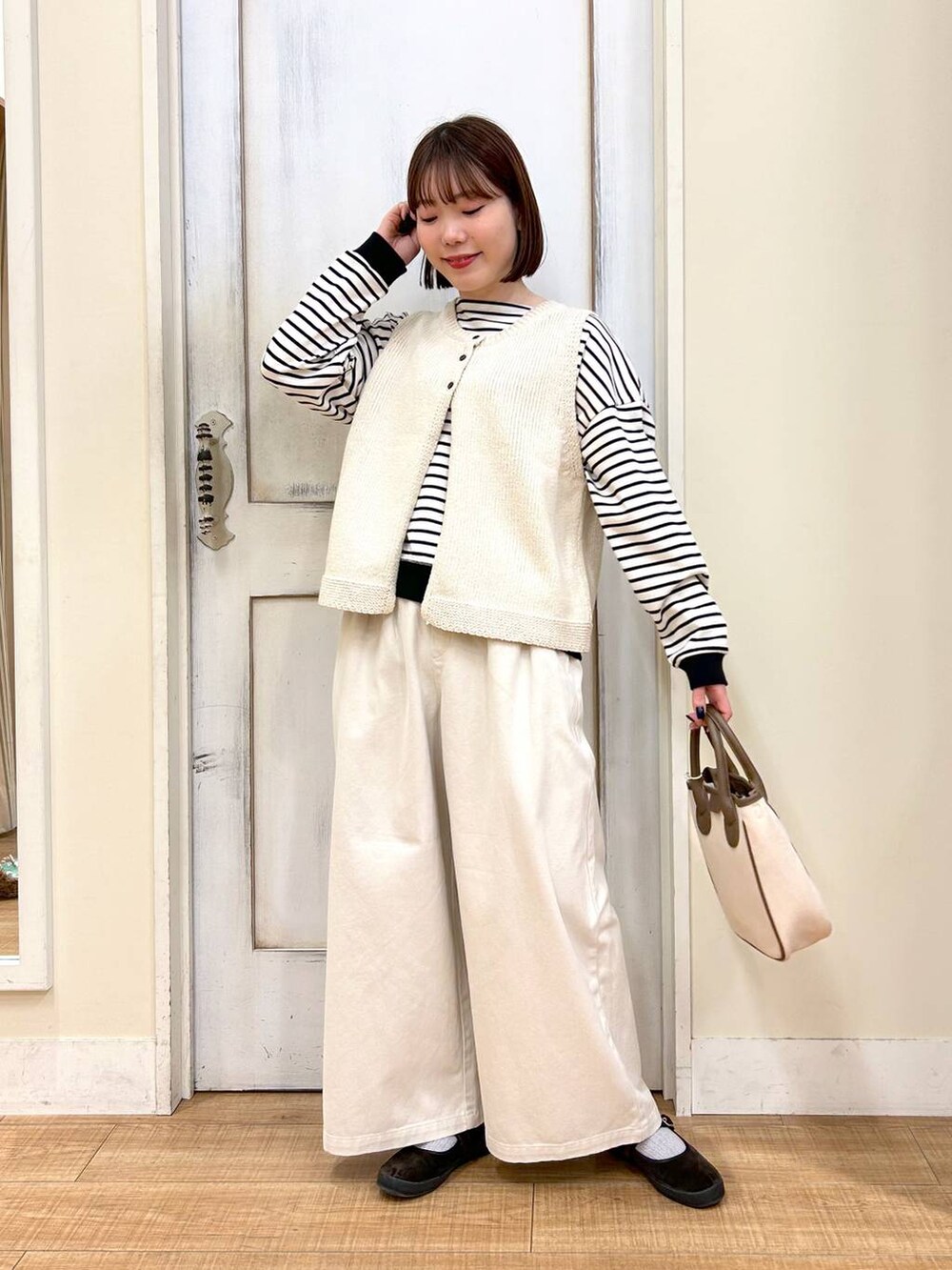 ホワイト系のトートバッグ、ブラウン系のスニーカー、ベージュ系のその他パンツを着用したレディースの春コーディネートの6枚目の写真