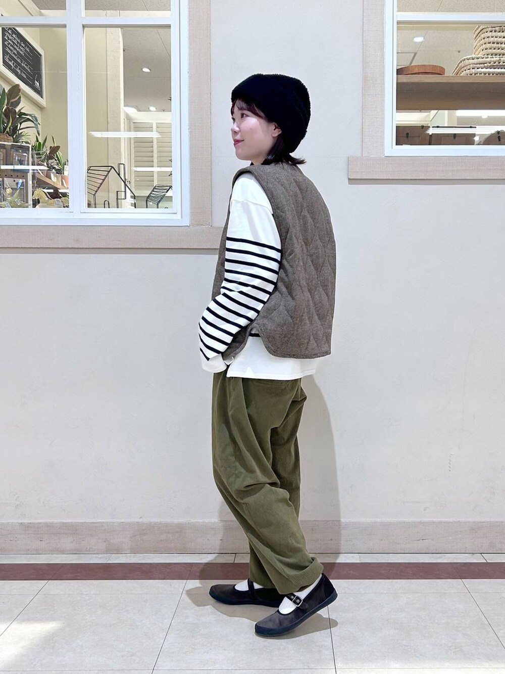 ベージュ系のベスト、グリーン系のその他パンツ、ブラウン系のスニーカーを着用したレディースの冬コーディネートの2枚目の写真