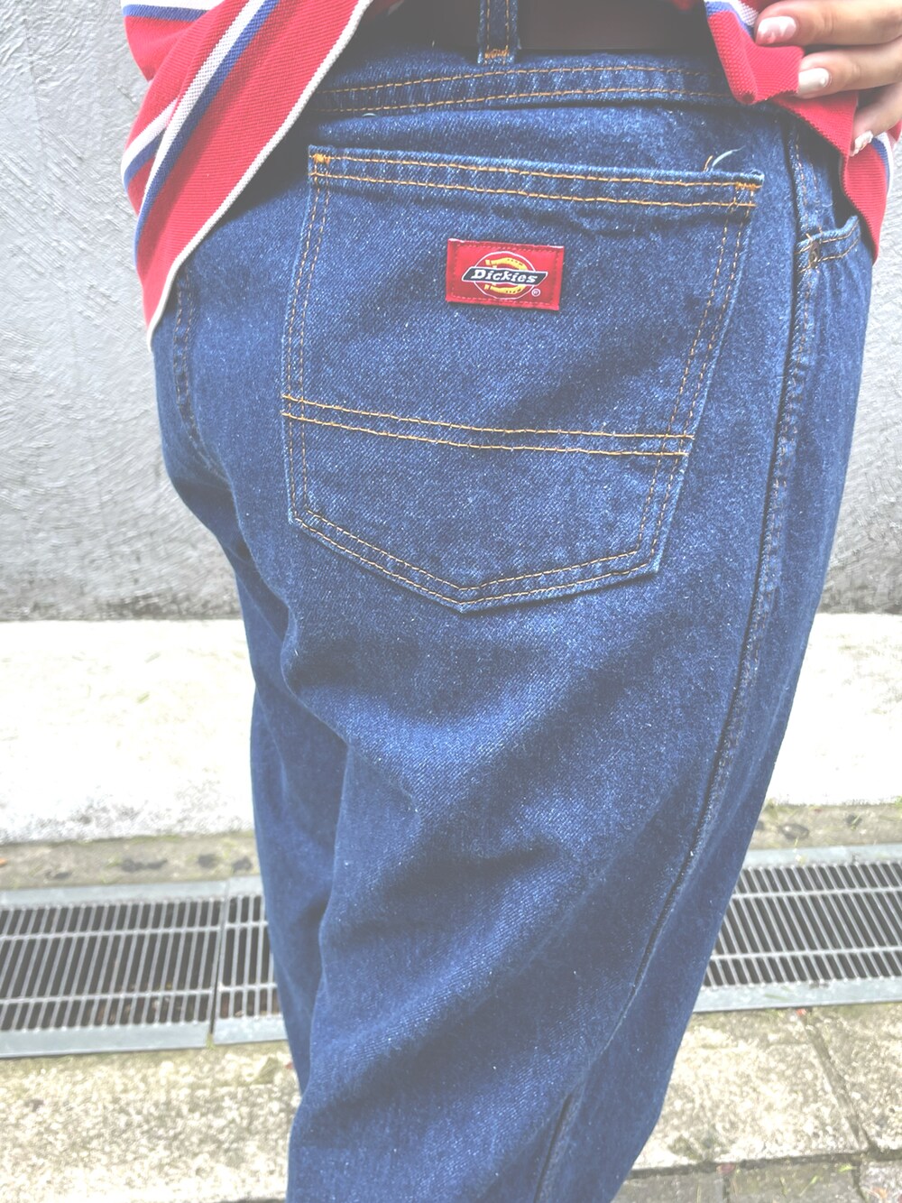 レッド系のポロシャツ、ピンク系のスニーカー、ブルー系のデニムパンツを着用したレディースの秋コーディネートの2枚目の写真