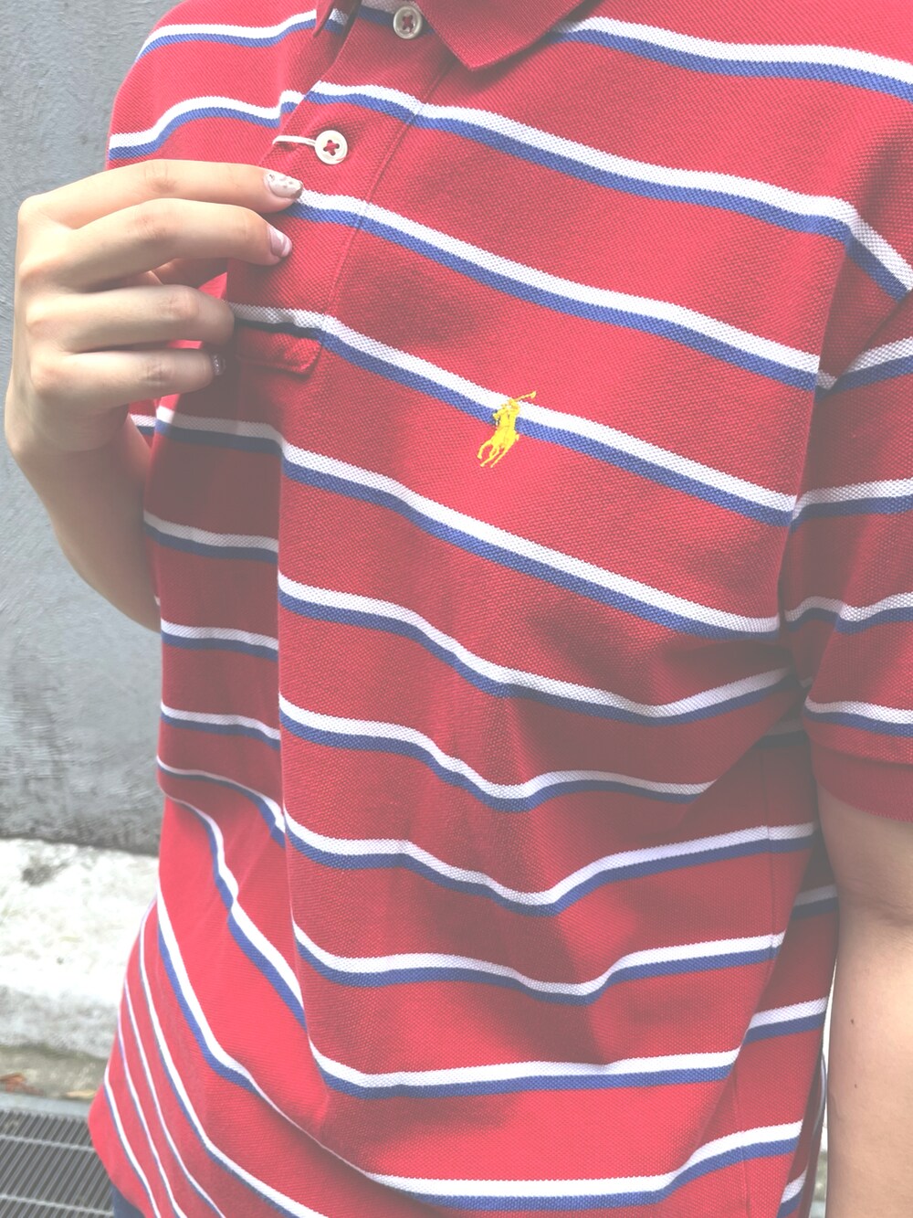 レッド系のポロシャツ、ピンク系のスニーカー、ブルー系のデニムパンツを着用したレディースの秋コーディネートの3枚目の写真