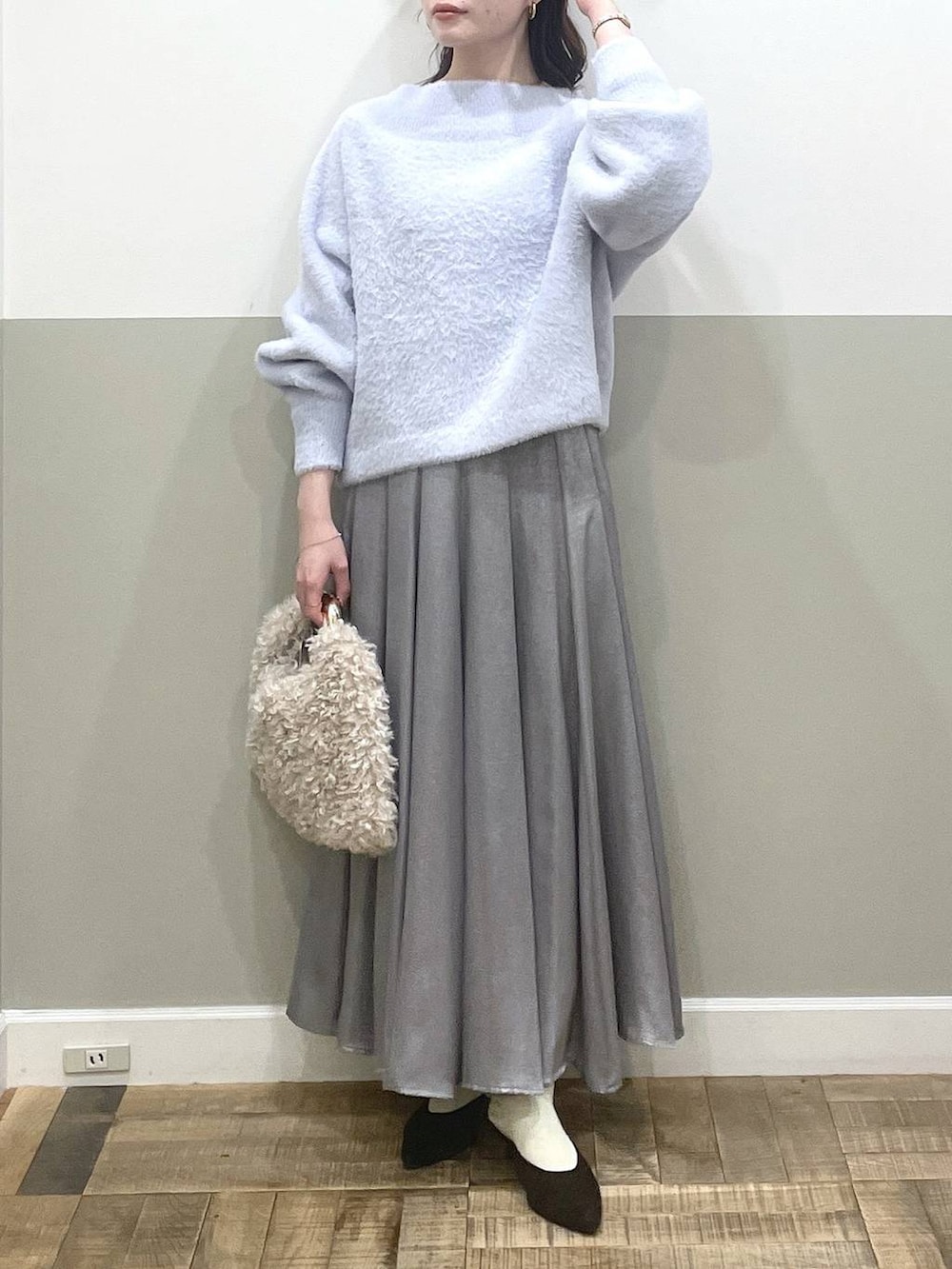 ブルー系のニット/セーター、ブラウン系のパンプス、グレー系のスカートを着用したレディースの秋コーディネートの4枚目の写真