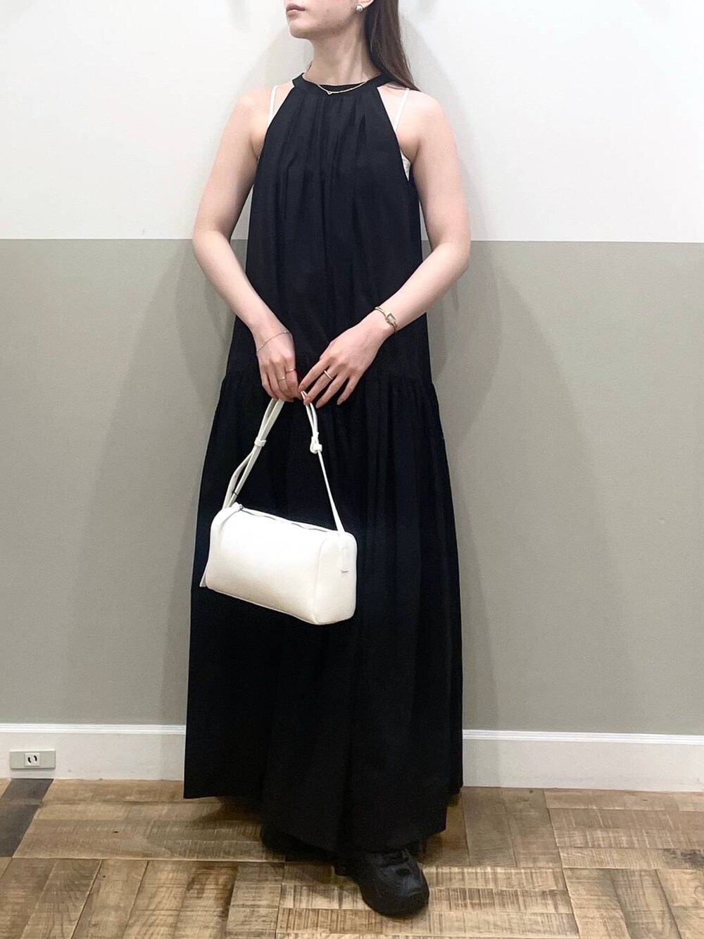 ホワイト系のハンドバッグ、ブラック系のワンピース、ホワイト系のキャミソールを着用したレディースの夏コーディネートの2枚目の写真