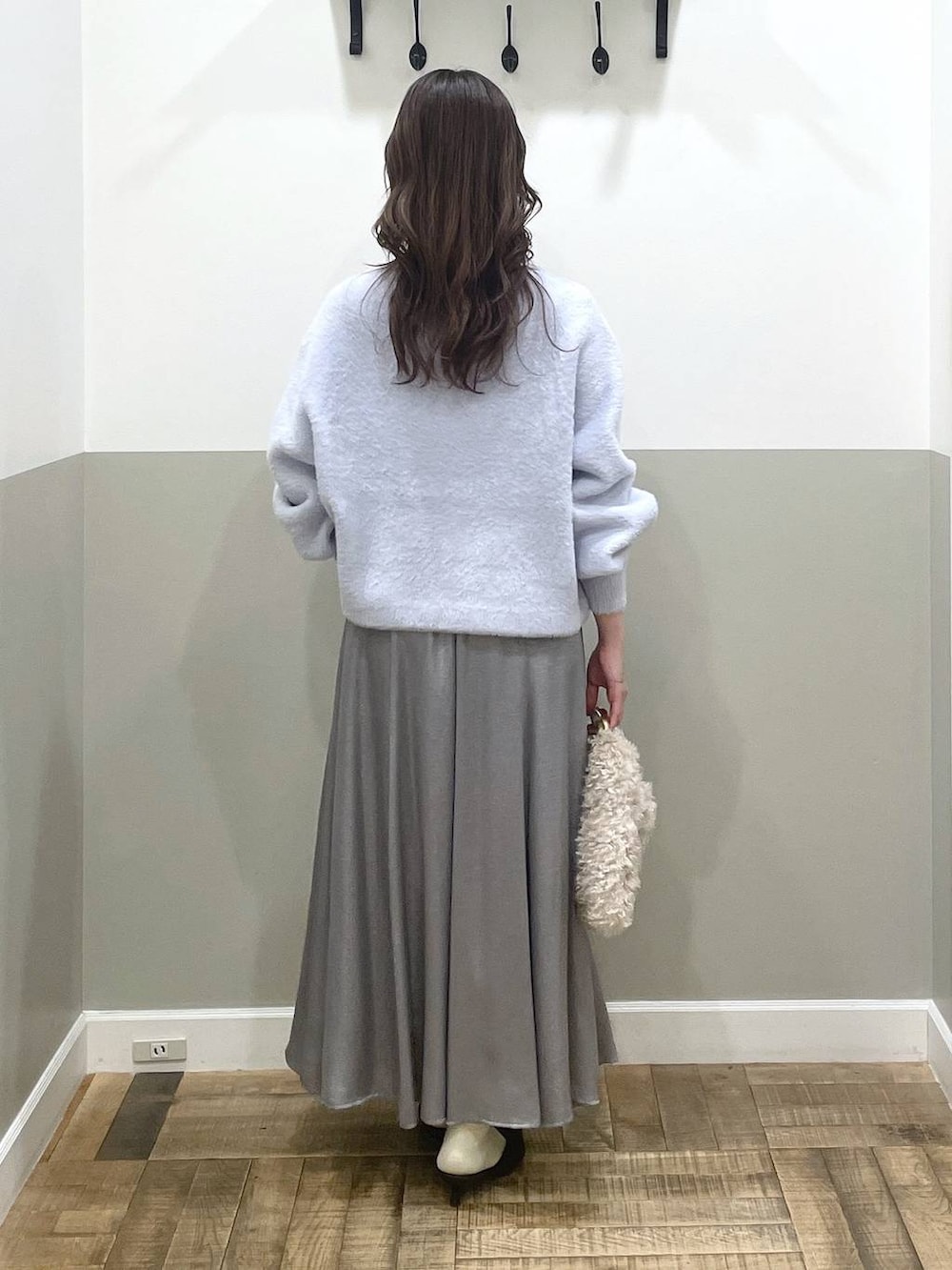 ブルー系のニット/セーター、ブラウン系のパンプス、グレー系のスカートを着用したレディースの秋コーディネートの3枚目の写真