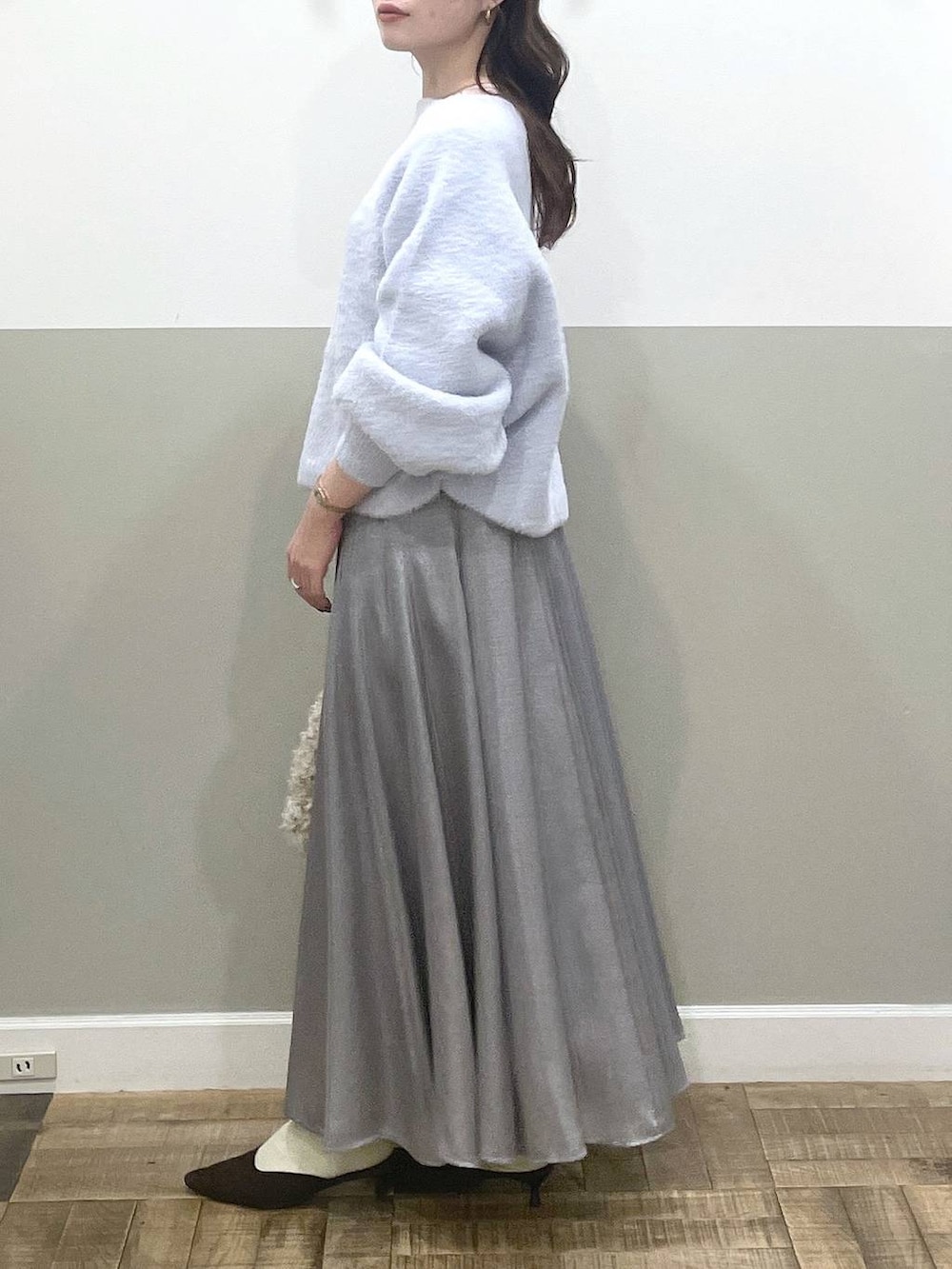 ブルー系のニット/セーター、ブラウン系のパンプス、グレー系のスカートを着用したレディースの秋コーディネートの2枚目の写真