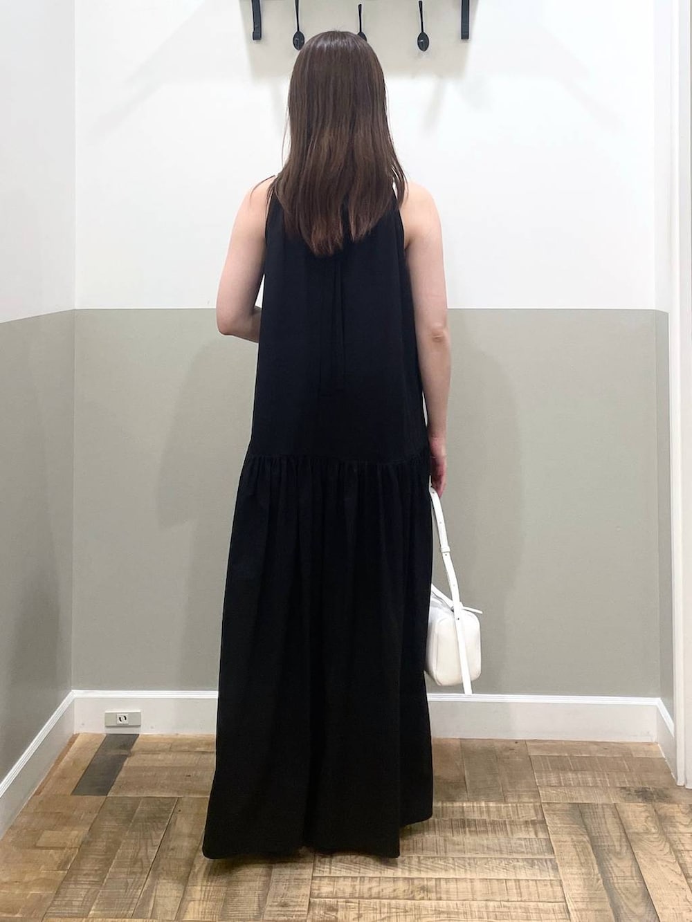 ホワイト系のハンドバッグ、ブラック系のワンピース、ホワイト系のキャミソールを着用したレディースの夏コーディネートの3枚目の写真