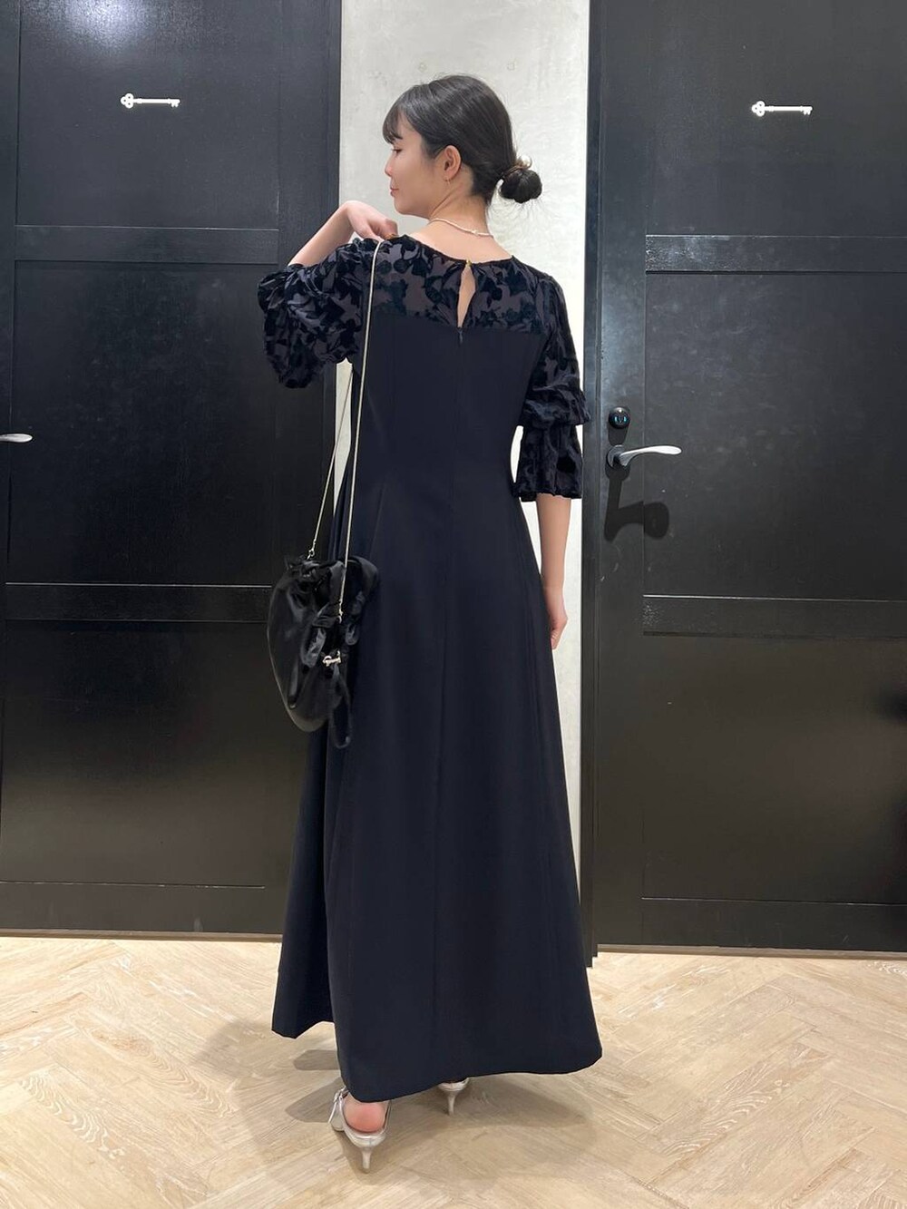 ブルー系のドレス、シルバー系のサンダル、ブラック系のショルダーバッグを着用したレディースの春コーディネートの2枚目の写真