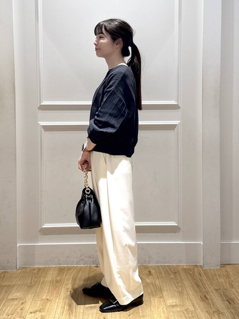 ホワイト系のスラックス、ブルー系のカーディガン/ボレロ、ブラック系のショルダーバッグを着用したレディースの冬コーディネートの3枚目の写真