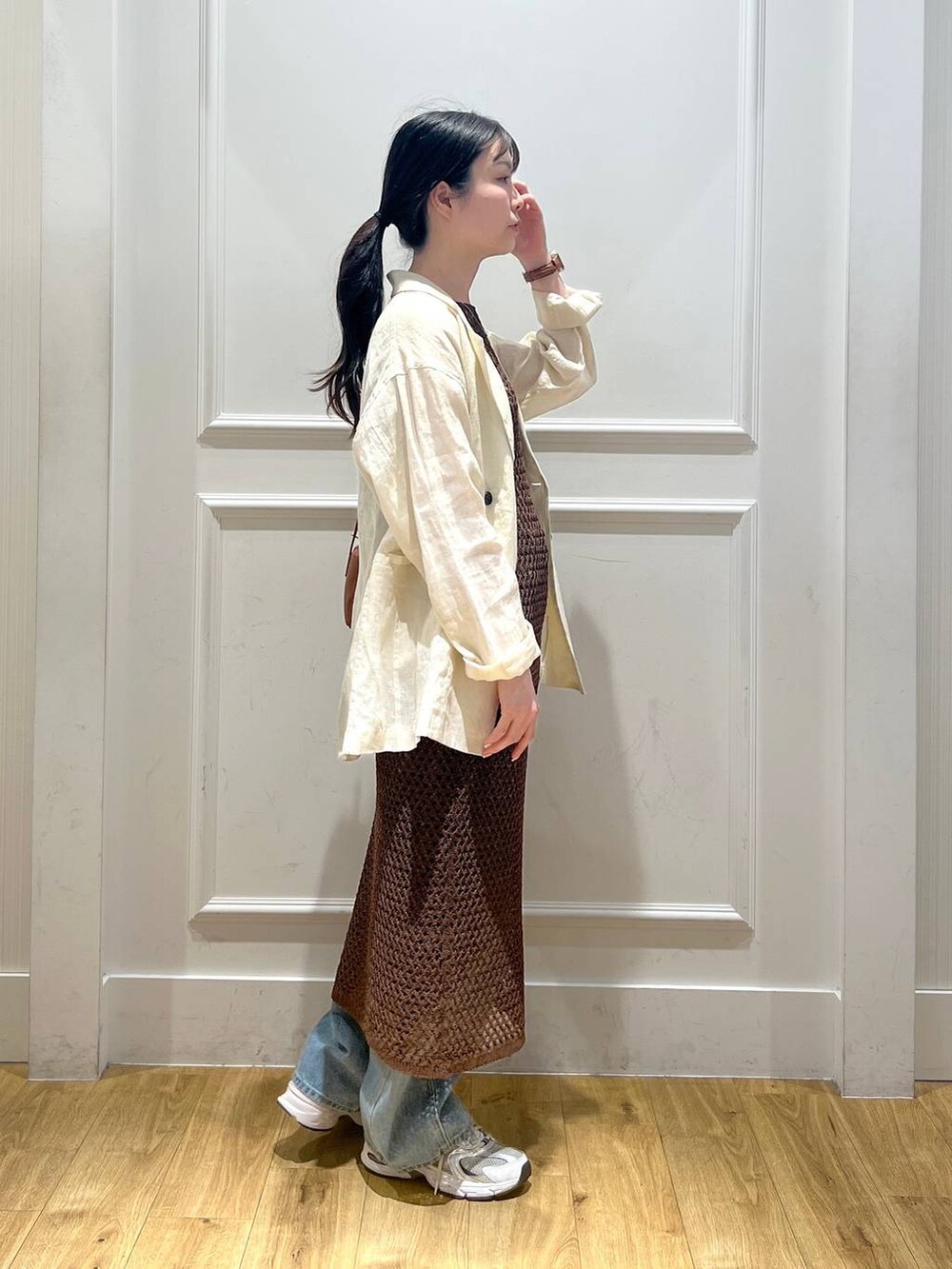 ブルー系のデニムパンツ、ブラウン系のハンドバッグ、ベージュ系のテーラードジャケットを着用したレディースの春コーディネートの2枚目の写真