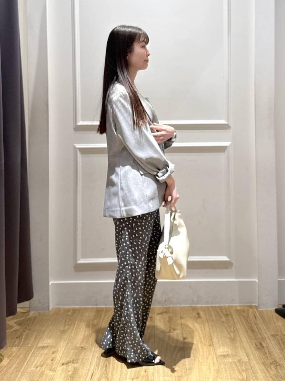 ブラック系のノーカラージャケット、ブラック系のベスト、ブラック系のサンダルを着用したレディースの春コーディネートの4枚目の写真