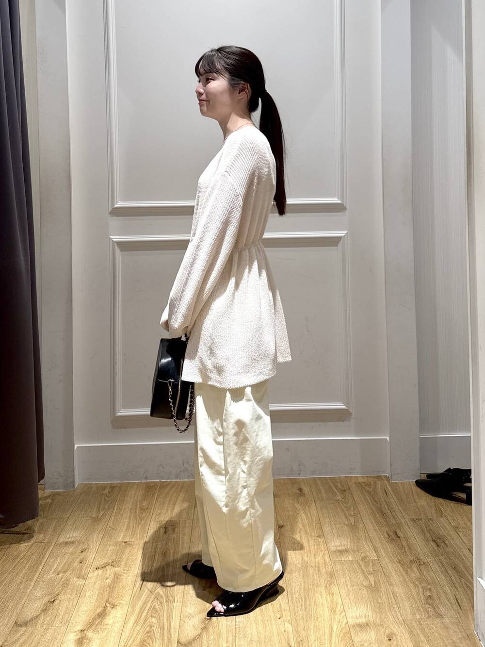 ホワイト系のカーディガン/ボレロ、ブラック系のサンダル、ブラック系のショルダーバッグを着用したレディースの春コーディネートの2枚目の写真