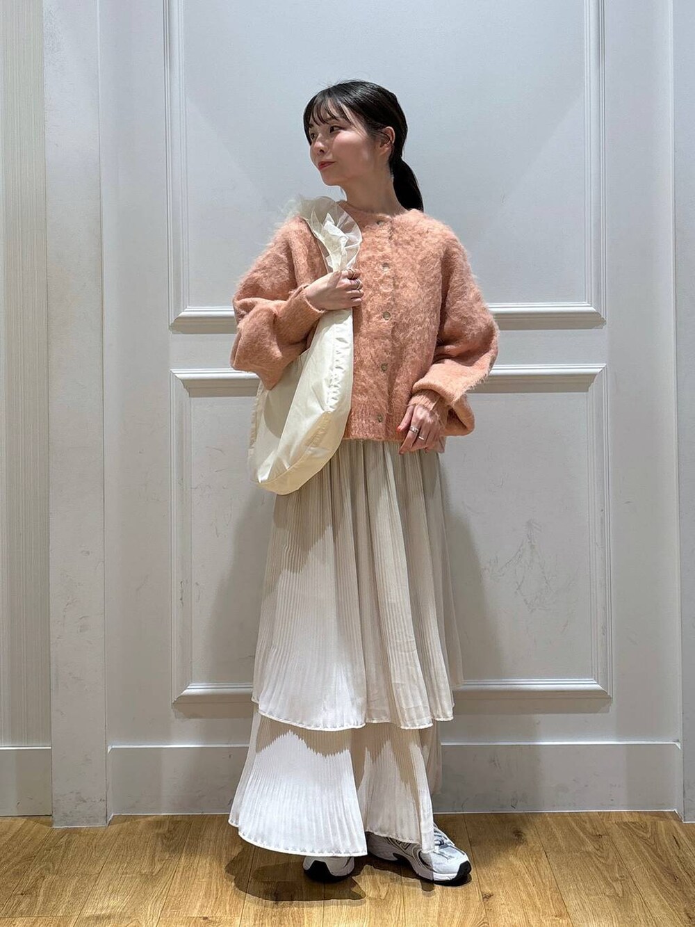 ホワイト系のスニーカー、ピンク系のカーディガン/ボレロ、ホワイト系のスカートを着用したレディースの秋コーディネートの5枚目の写真