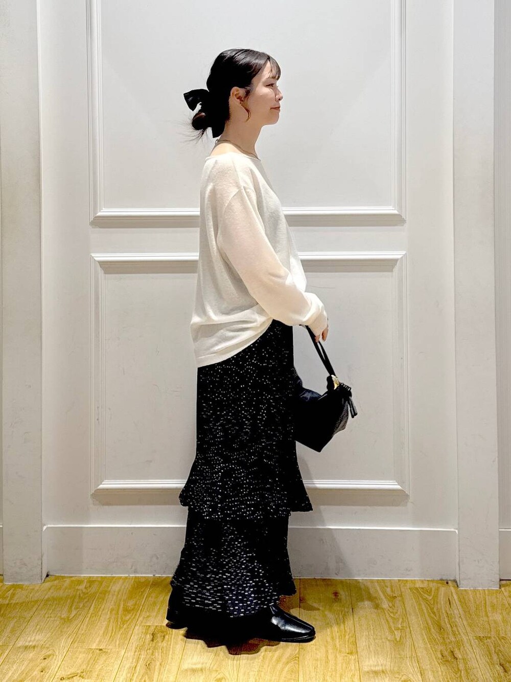 グレー系のスカート、ブラック系のブーツ、ブラック系のショルダーバッグを着用したレディースの秋コーディネートの4枚目の写真