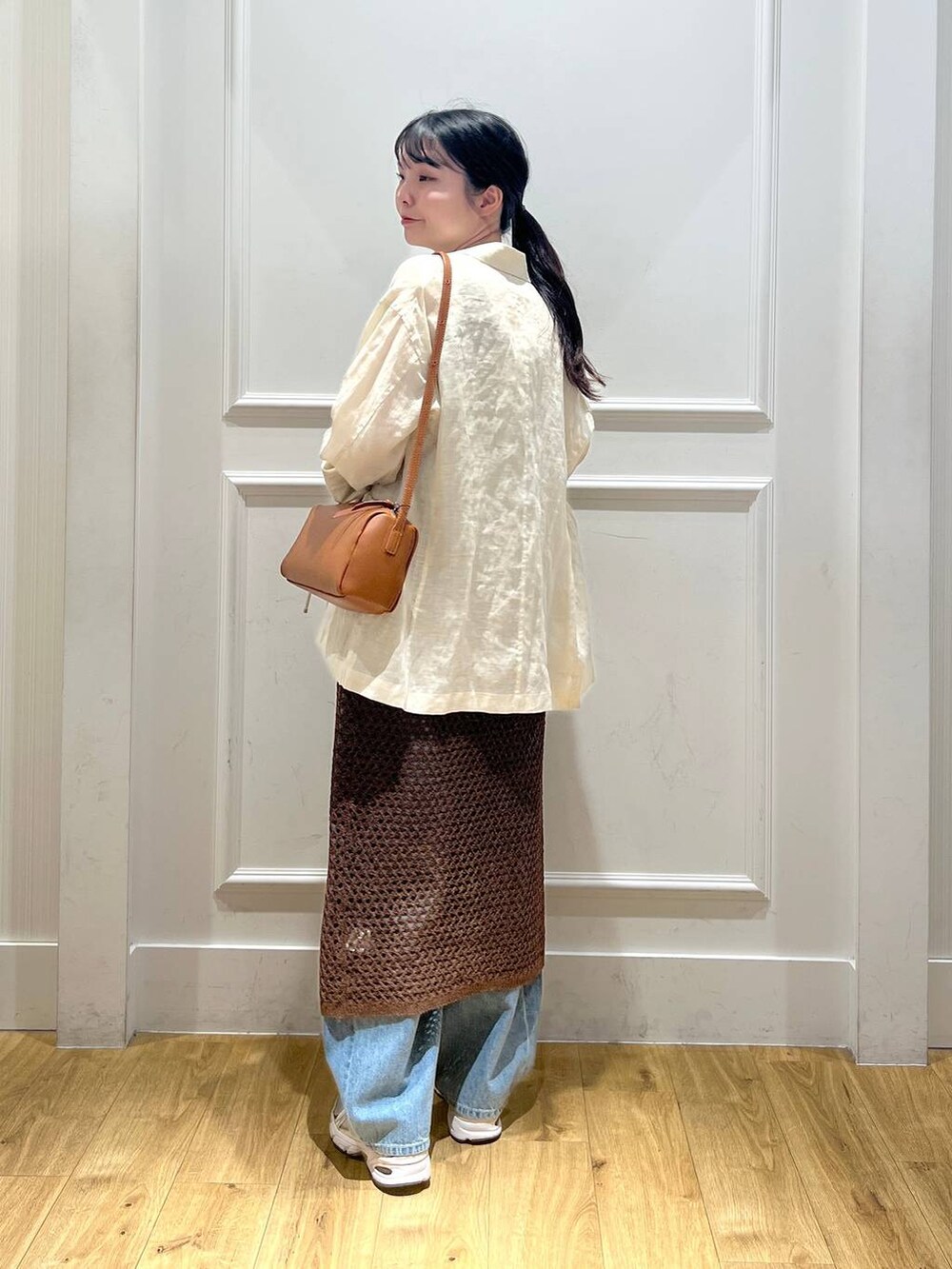 ブルー系のデニムパンツ、ブラウン系のハンドバッグ、ベージュ系のテーラードジャケットを着用したレディースの春コーディネートの3枚目の写真