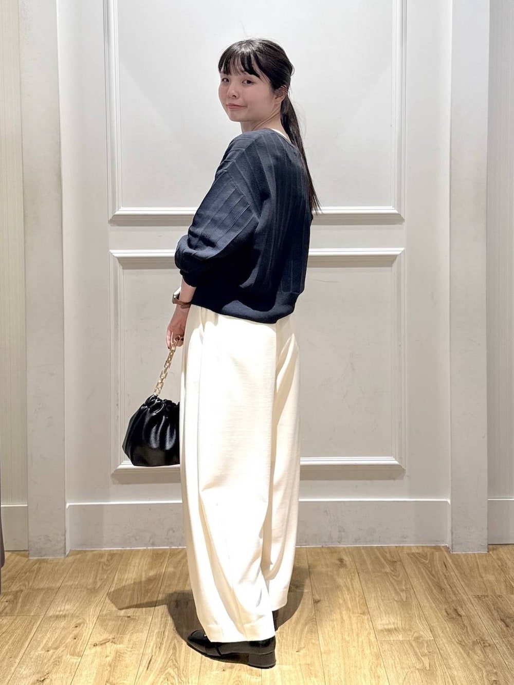 ホワイト系のスラックス、ブルー系のカーディガン/ボレロ、ブラック系のショルダーバッグを着用したレディースの冬コーディネートの4枚目の写真