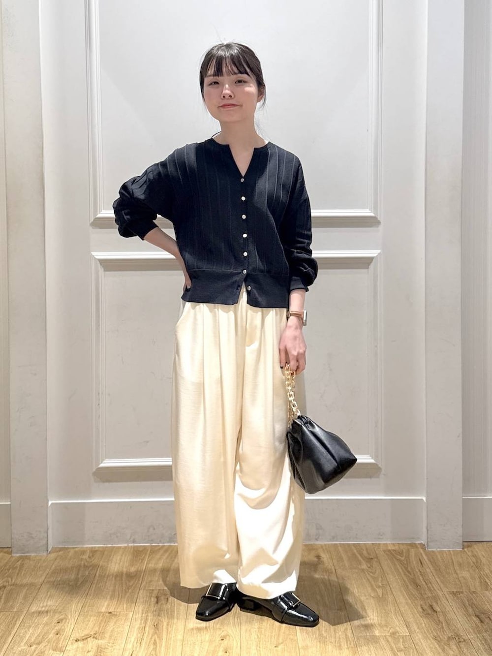 ホワイト系のスラックス、ブルー系のカーディガン/ボレロ、ブラック系のショルダーバッグを着用したレディースの冬コーディネートの2枚目の写真