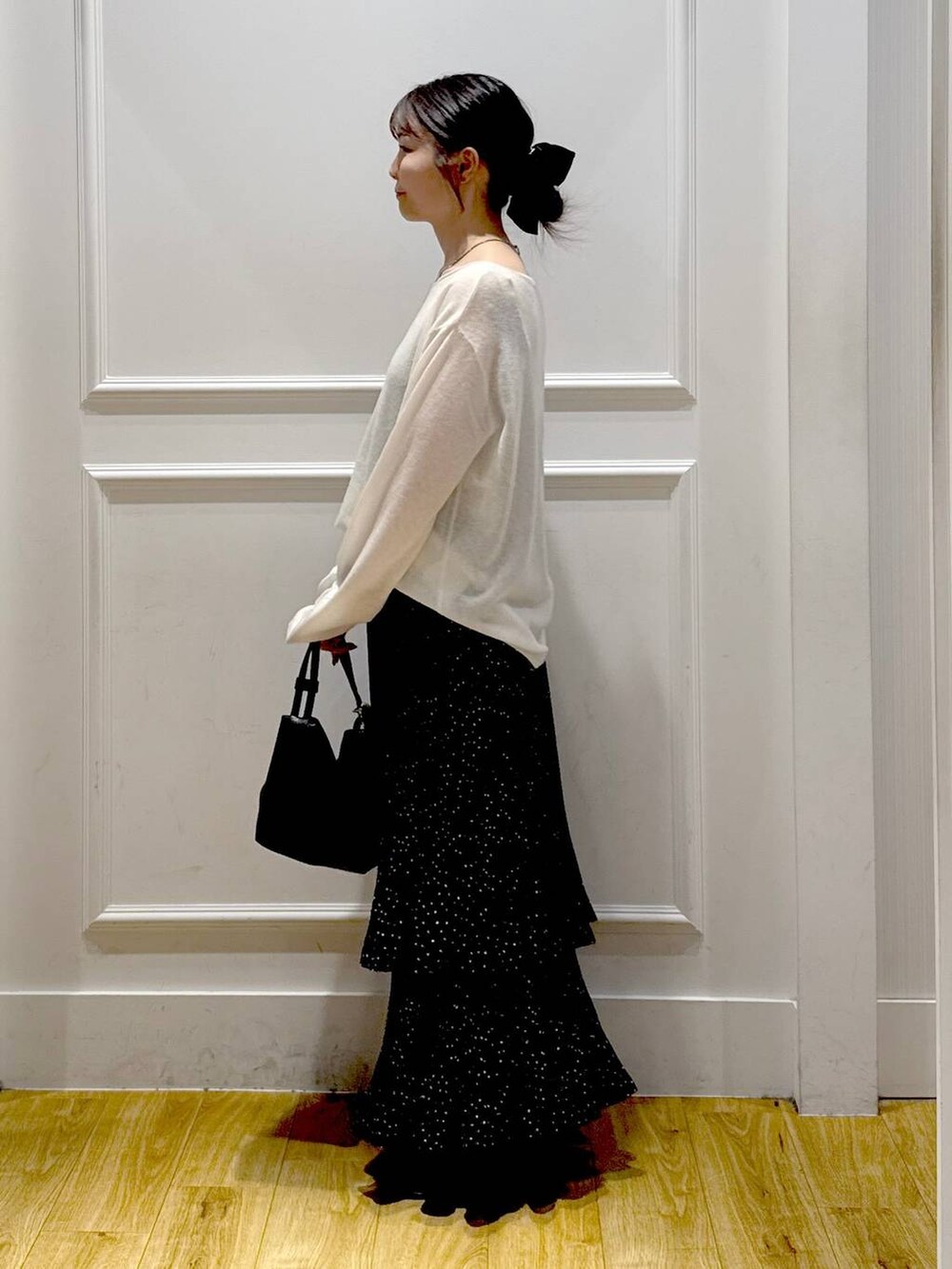 グレー系のスカート、ブラック系のブーツ、ブラック系のショルダーバッグを着用したレディースの秋コーディネートの2枚目の写真