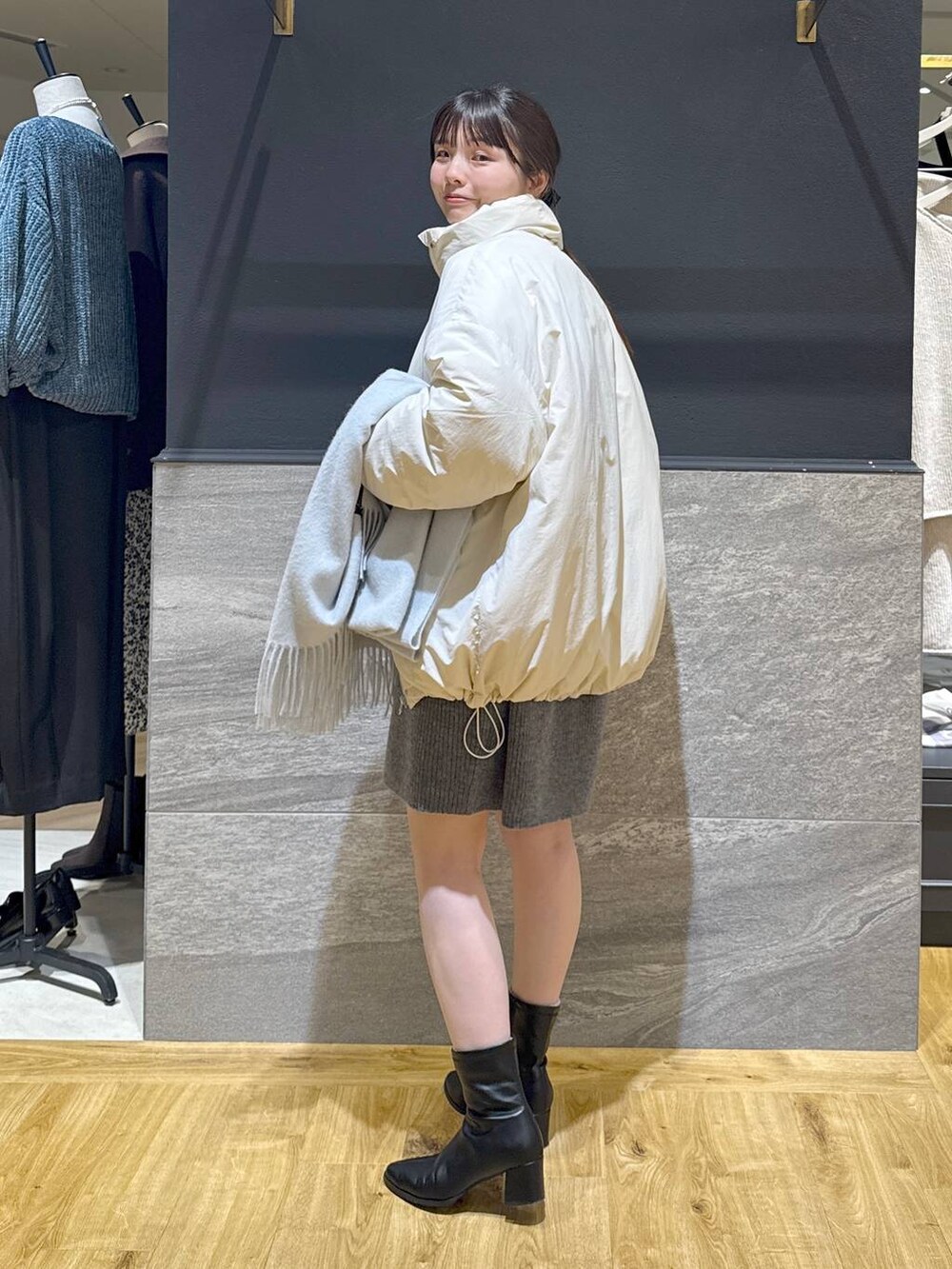 ブラック系のブーツ、ホワイト系のブルゾン、グレー系のワンピースを着用したレディースの冬コーディネートの3枚目の写真