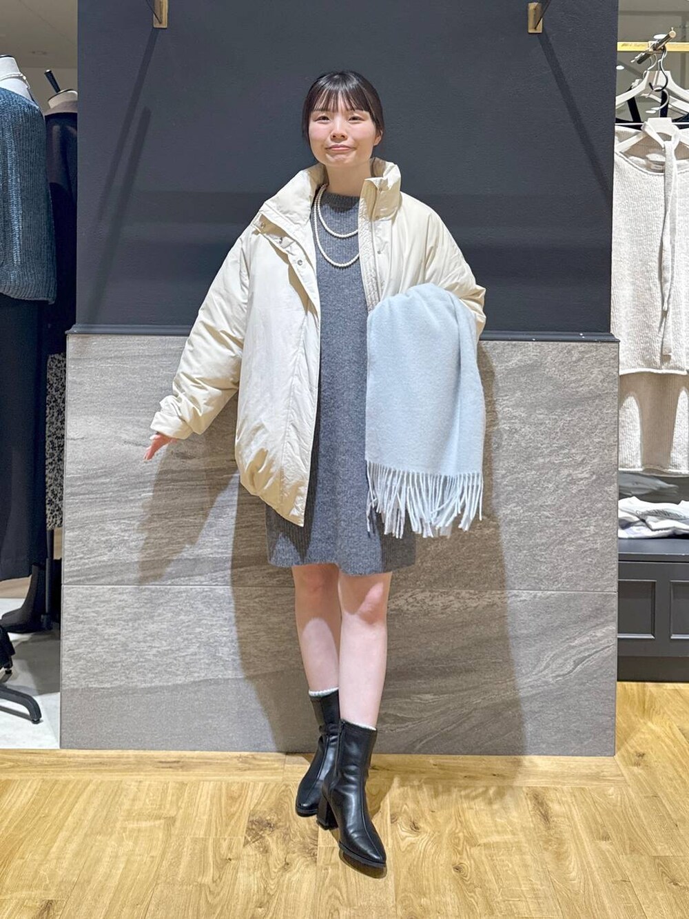ブラック系のブーツ、ホワイト系のブルゾン、グレー系のワンピースを着用したレディースの冬コーディネートの5枚目の写真