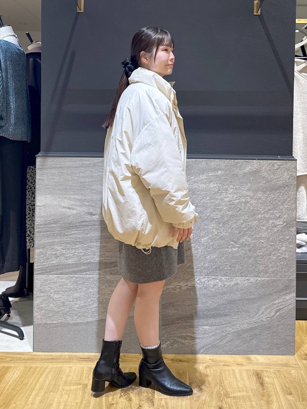 ブラック系のブーツ、ホワイト系のブルゾン、グレー系のワンピースを着用したレディースの冬コーディネートの4枚目の写真