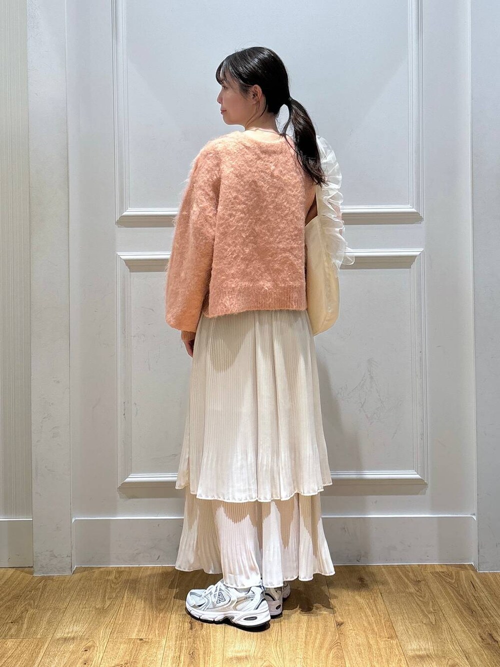 ホワイト系のスニーカー、ピンク系のカーディガン/ボレロ、ホワイト系のスカートを着用したレディースの秋コーディネートの3枚目の写真