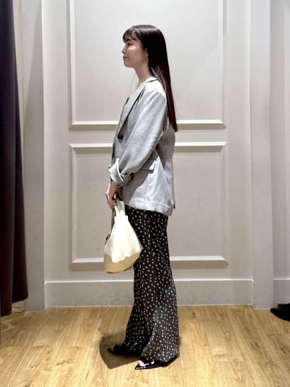 ブラック系のノーカラージャケット、ブラック系のベスト、ブラック系のサンダルを着用したレディースの春コーディネートの2枚目の写真