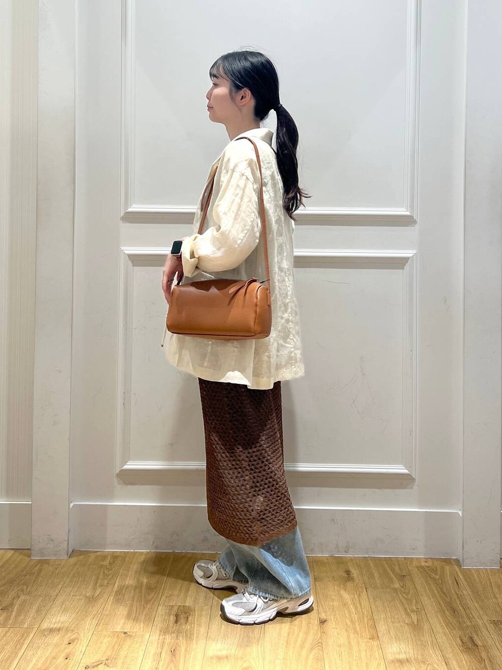 ブルー系のデニムパンツ、ブラウン系のハンドバッグ、ベージュ系のテーラードジャケットを着用したレディースの春コーディネートの4枚目の写真