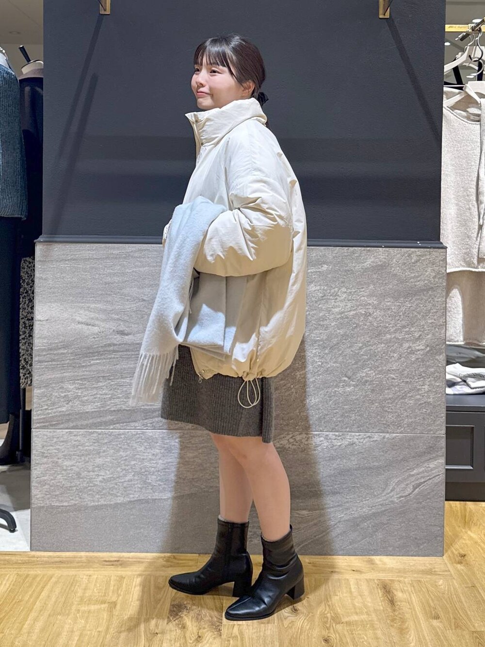 ブラック系のブーツ、ホワイト系のブルゾン、グレー系のワンピースを着用したレディースの冬コーディネートの2枚目の写真