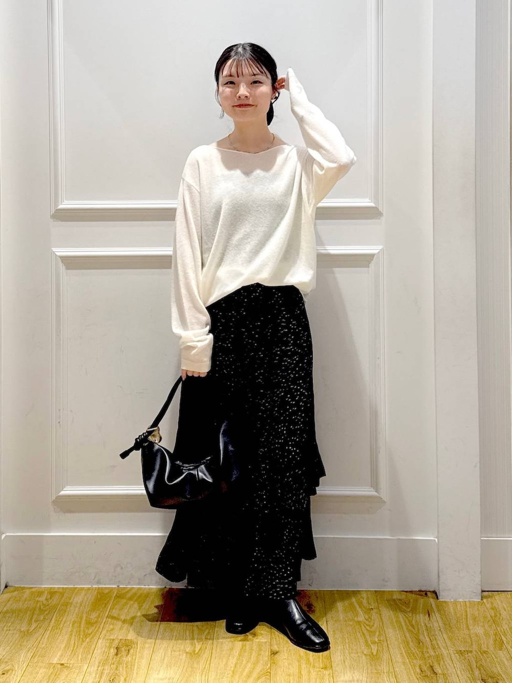 グレー系のスカート、ブラック系のブーツ、ブラック系のショルダーバッグを着用したレディースの秋コーディネートの5枚目の写真