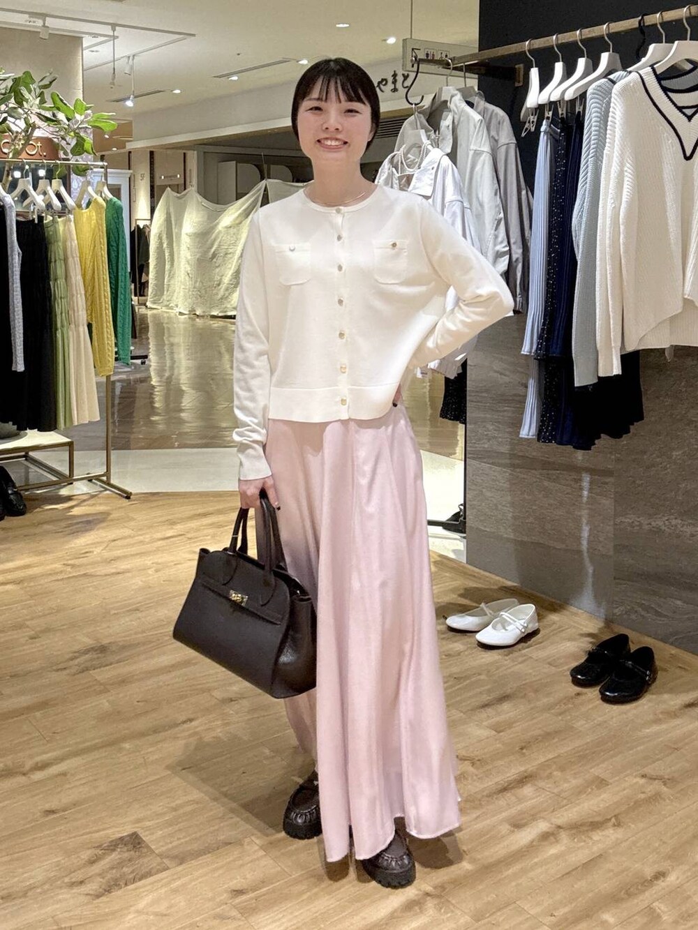 ピンク系のスカート、ブラウン系のローファー、ブラック系のショルダーバッグを着用したレディースの春コーディネートの5枚目の写真