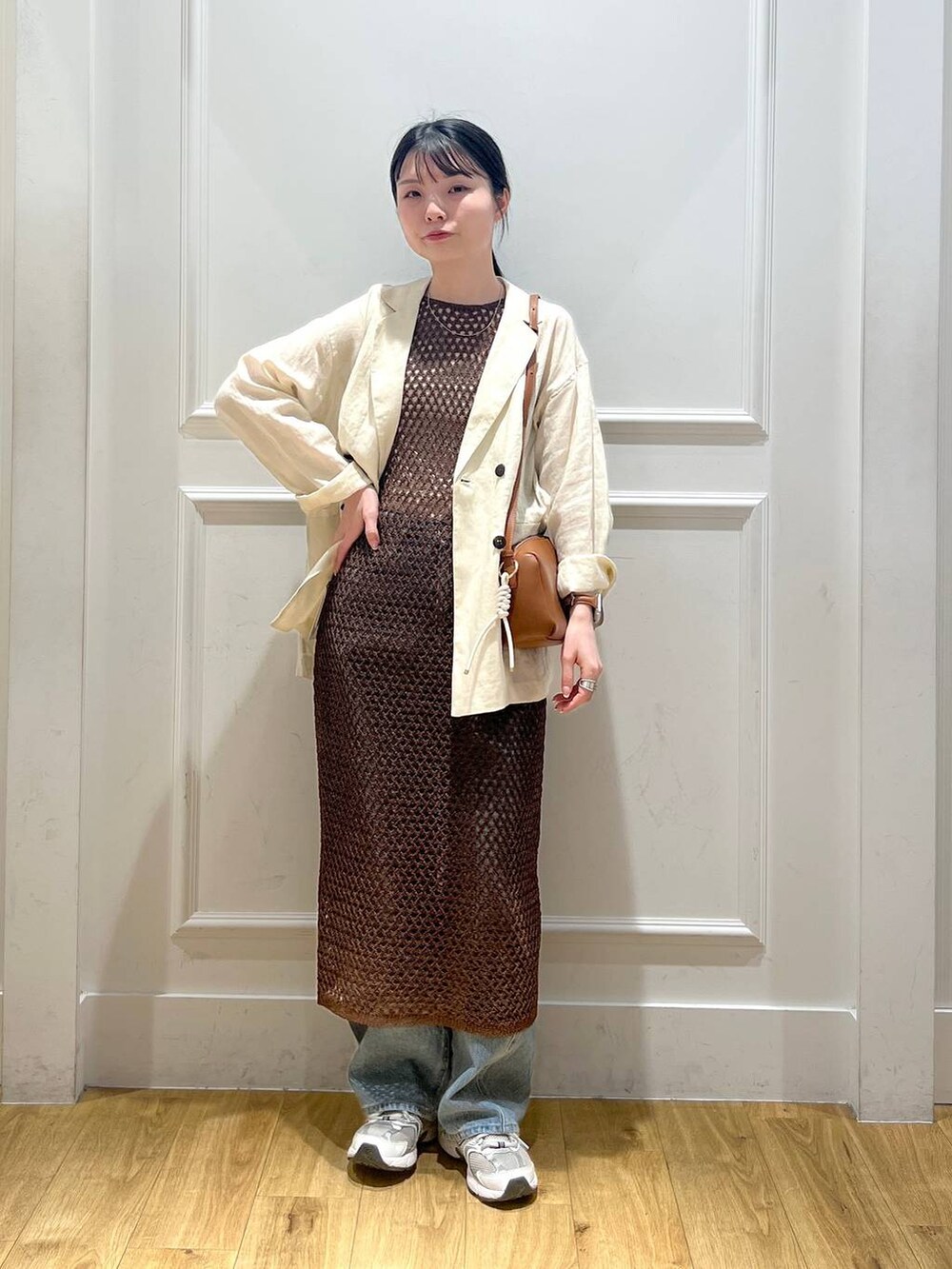 ブルー系のデニムパンツ、ブラウン系のハンドバッグ、ベージュ系のテーラードジャケットを着用したレディースの春コーディネートの5枚目の写真