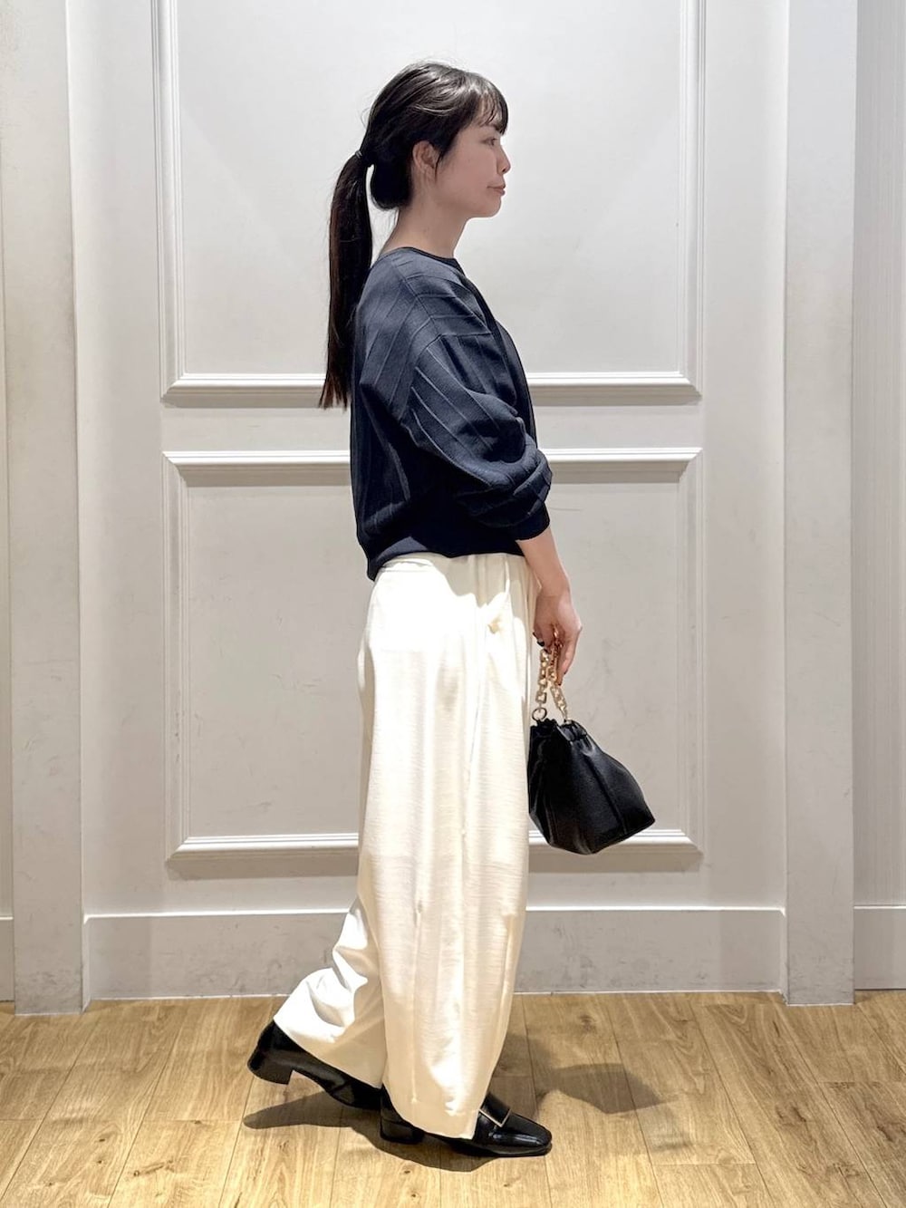 ホワイト系のスラックス、ブルー系のカーディガン/ボレロ、ブラック系のショルダーバッグを着用したレディースの冬コーディネートの5枚目の写真