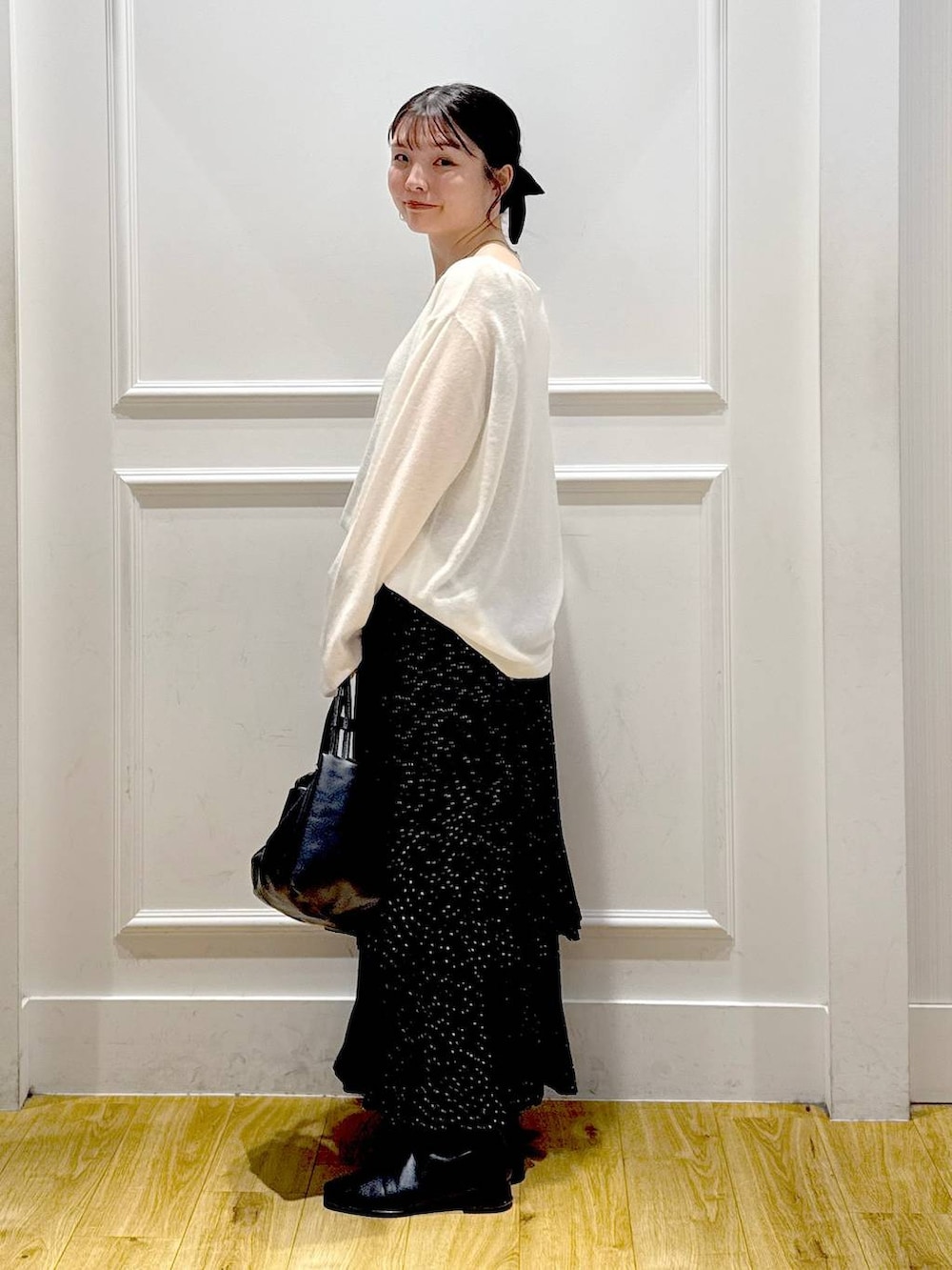 グレー系のスカート、ブラック系のブーツ、ブラック系のショルダーバッグを着用したレディースの秋コーディネートの3枚目の写真