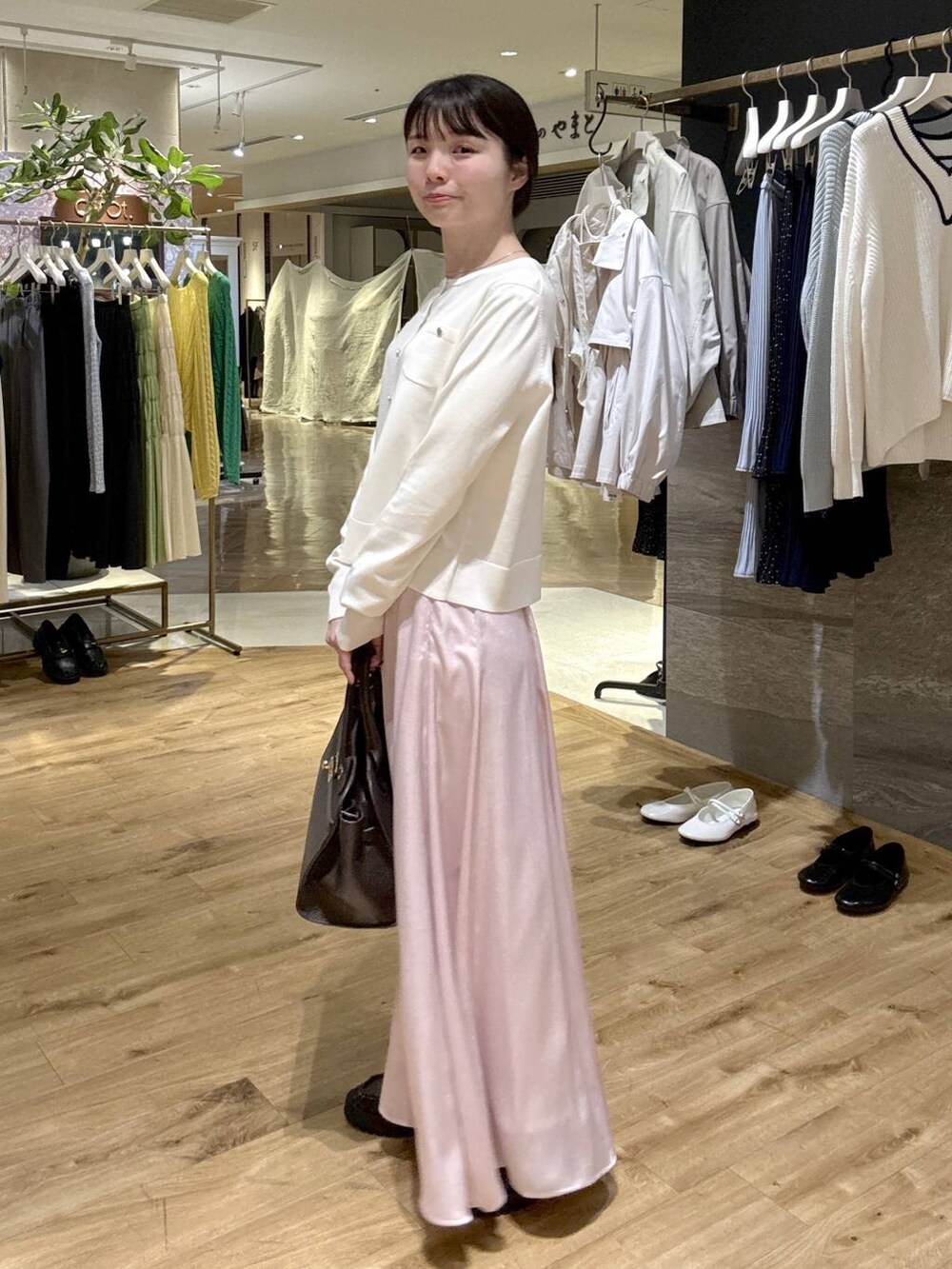 ピンク系のスカート、ブラウン系のローファー、ブラック系のショルダーバッグを着用したレディースの春コーディネートの2枚目の写真