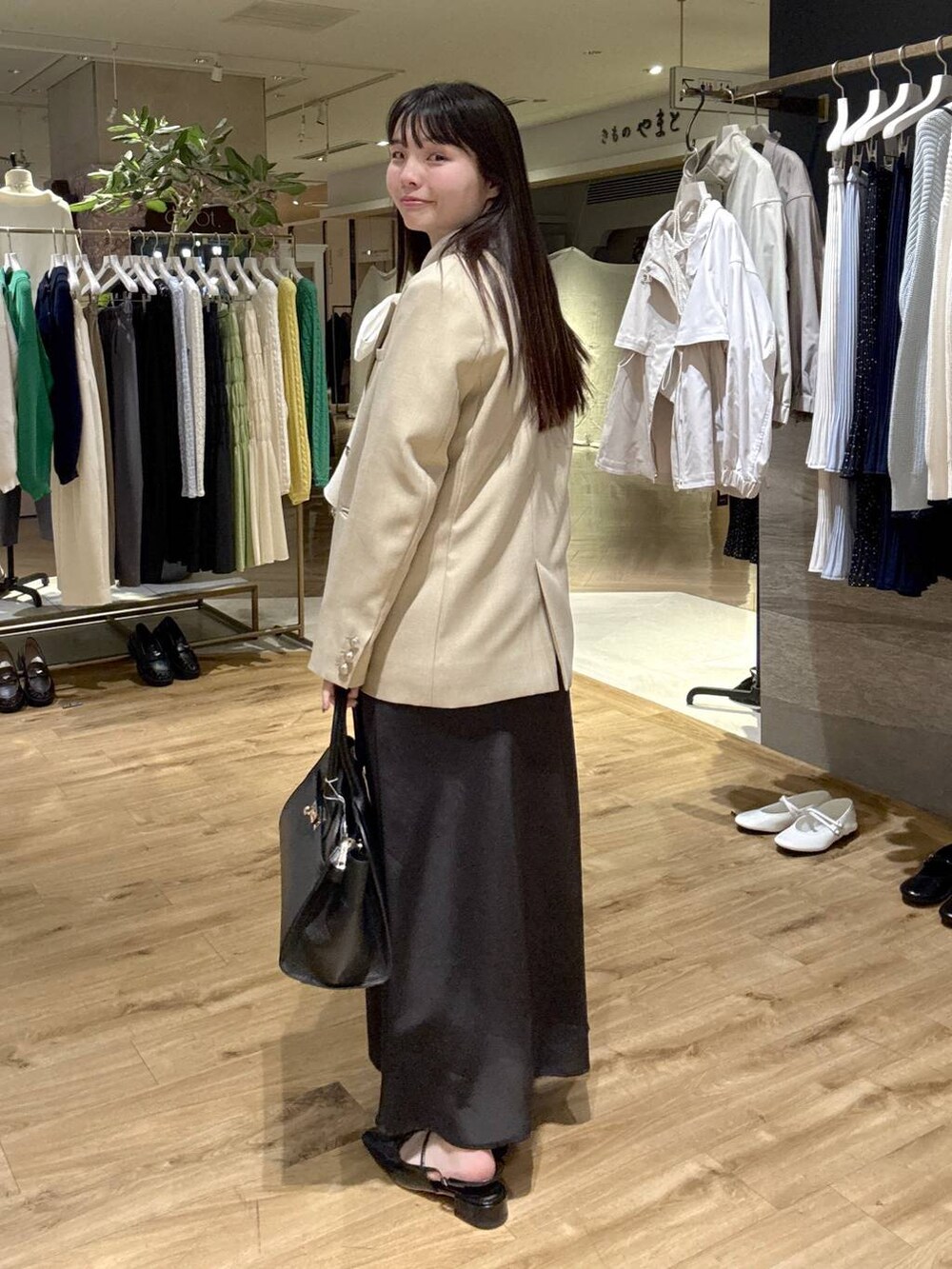 ホワイト系のシャツ/ブラウス、ベージュ系のテーラードジャケット、ブラック系のショルダーバッグを着用したレディースの春コーディネートの2枚目の写真