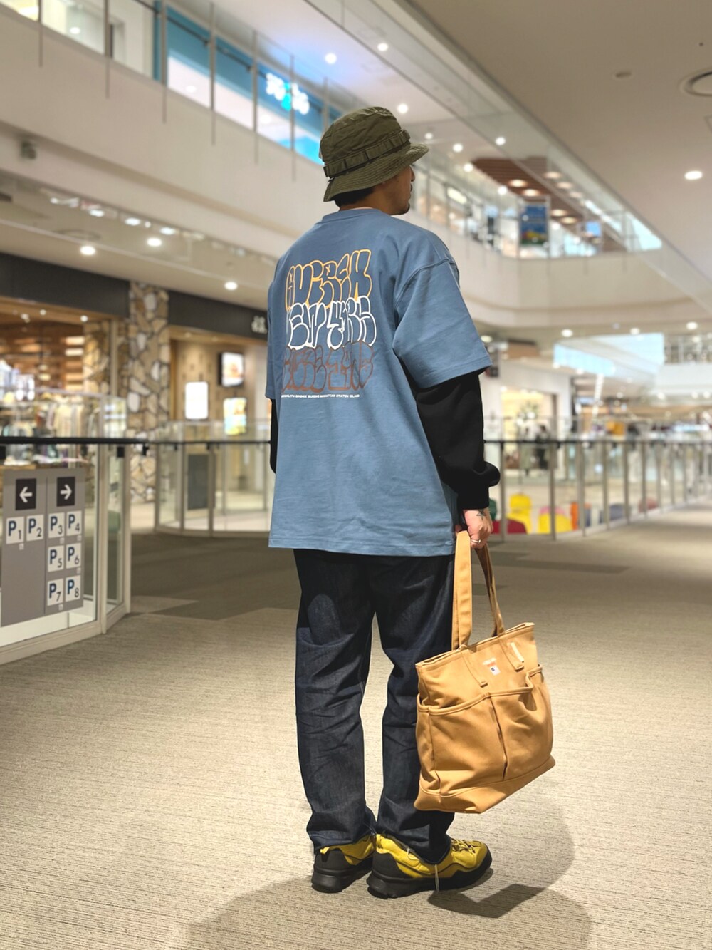 ブラウン系のトートバッグ、グレー系のTシャツ/カットソー、グリーン系のハットを着用したメンズの夏コーディネートの2枚目の写真