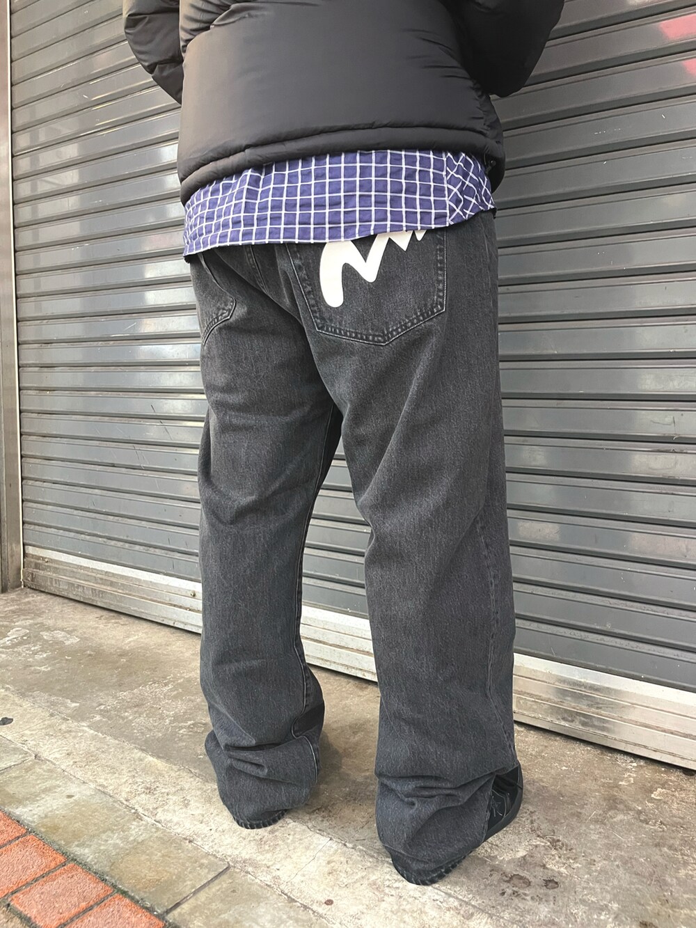 ブラック系のダウンジャケット/コート、ブラック系のデニムパンツ、ブルー系のシャツ/ブラウスを着用したメンズの秋コーディネートの4枚目の写真