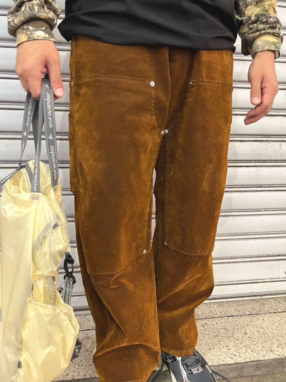 ブラウン系のデニムパンツ、ホワイト系のトートバッグ、ブラック系のTシャツ/カットソーを着用したメンズの秋コーディネートの4枚目の写真