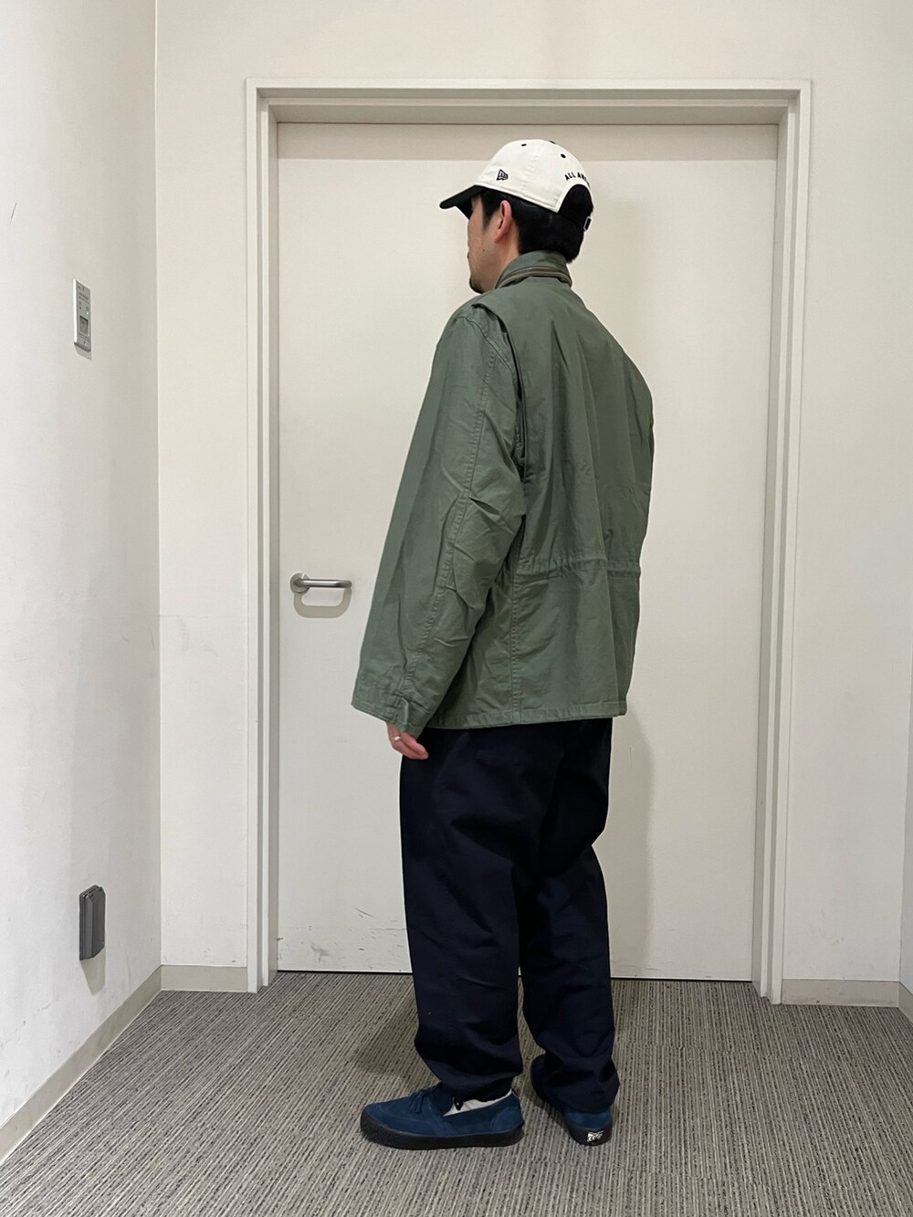 ブルー系のその他パンツ、グリーン系のミリタリージャケット、ホワイト系のキャップを着用したメンズの春コーディネートの3枚目の写真