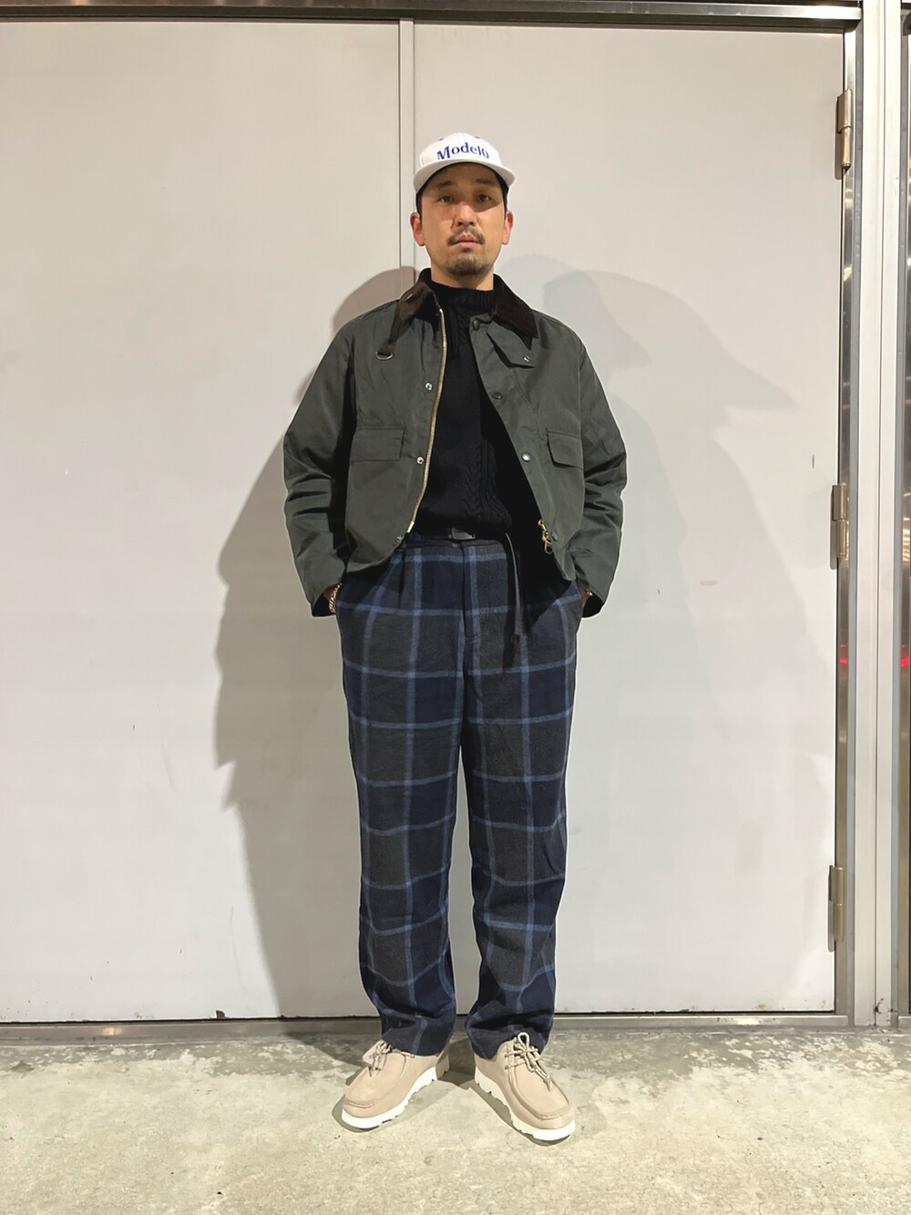 ブラック系のニット/セーター、ブルー系のスラックス、グリーン系のブルゾンを着用したメンズの秋コーディネートの2枚目の写真