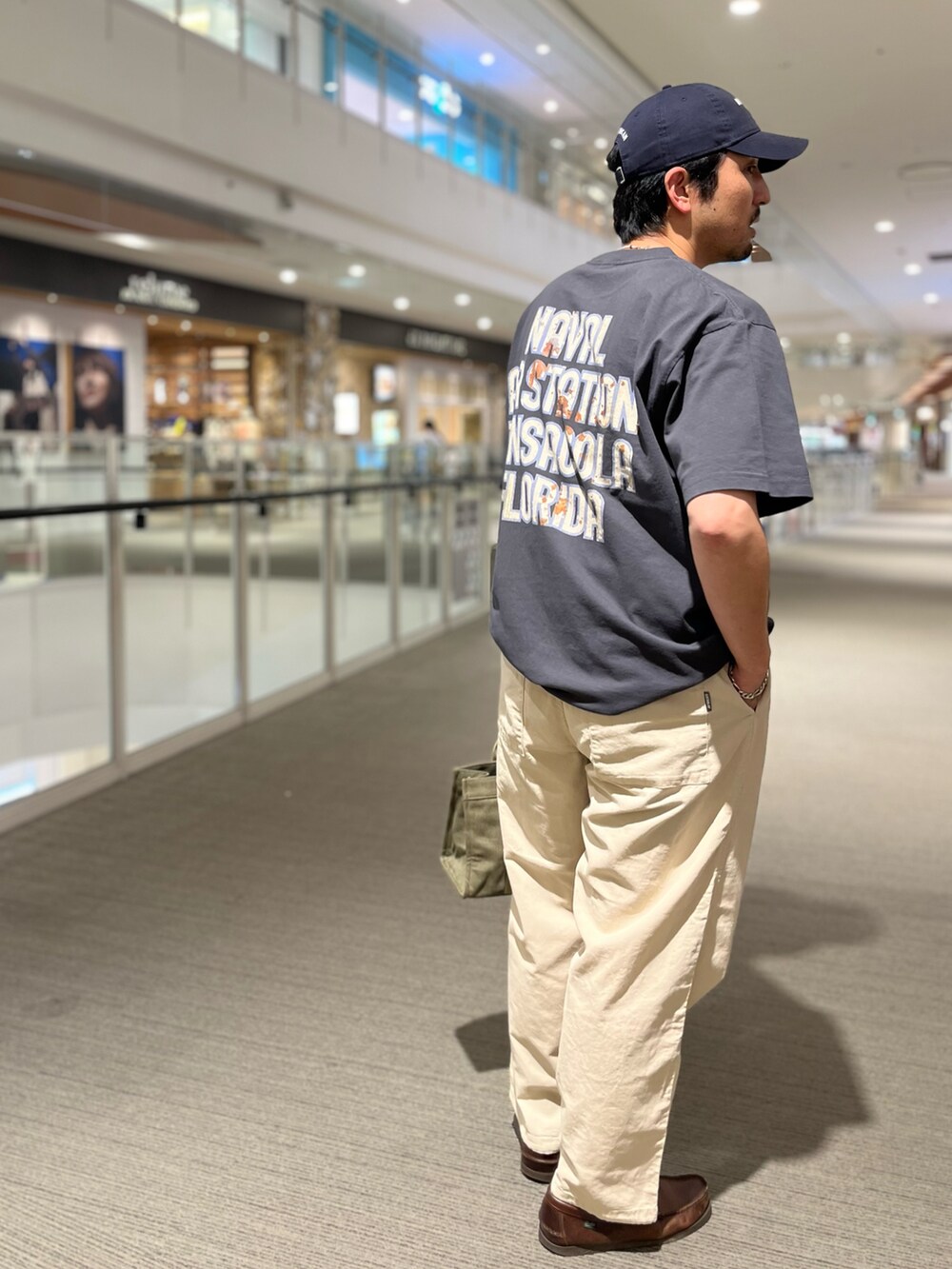 ブラック系のTシャツ/カットソー、ベージュ系のカーゴパンツ、グリーン系のトートバッグを着用したメンズの春コーディネートの2枚目の写真