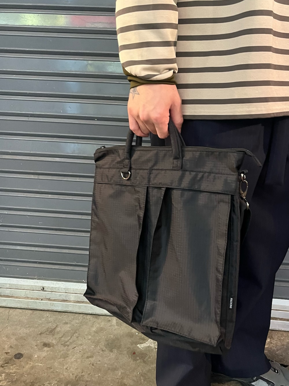 ブラック系のショルダーバッグ、ベージュ系のTシャツ/カットソー、ブルー系のキャップを着用したメンズの冬コーディネートの4枚目の写真