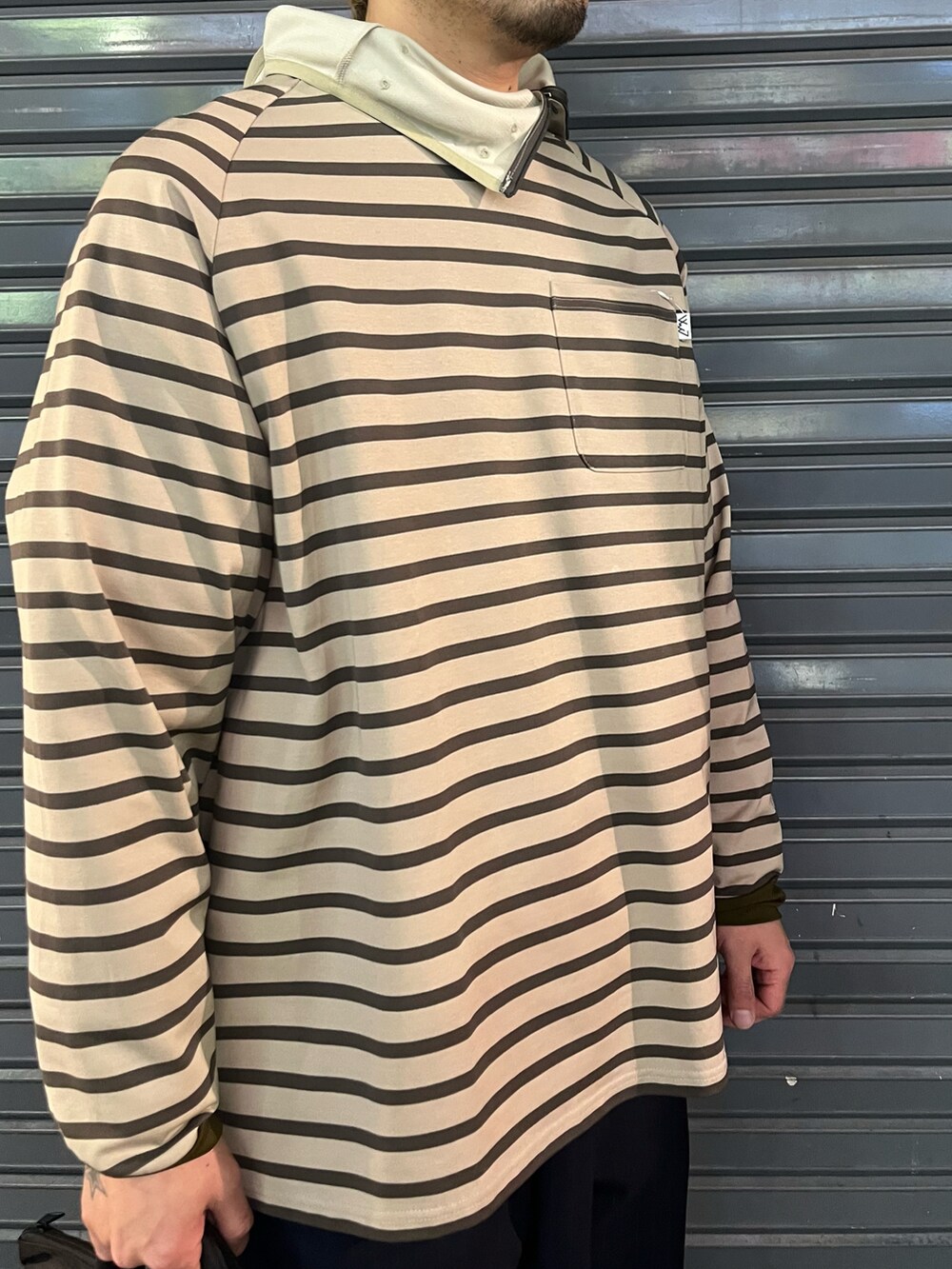 ブラック系のショルダーバッグ、ベージュ系のTシャツ/カットソー、ブルー系のキャップを着用したメンズの冬コーディネートの2枚目の写真