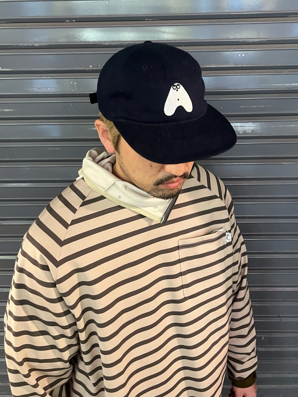 ブラック系のショルダーバッグ、ベージュ系のTシャツ/カットソー、ブルー系のキャップを着用したメンズの冬コーディネートの3枚目の写真