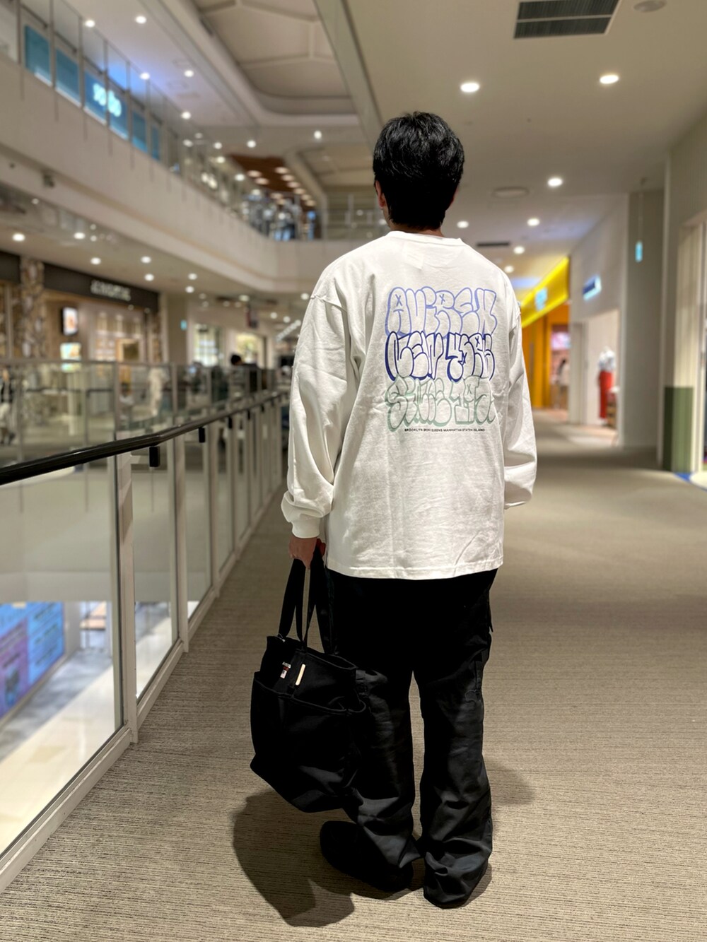 ブラック系のトートバッグ、その他のカーゴパンツ、ホワイト系のTシャツ/カットソーを着用したメンズの夏コーディネートの2枚目の写真