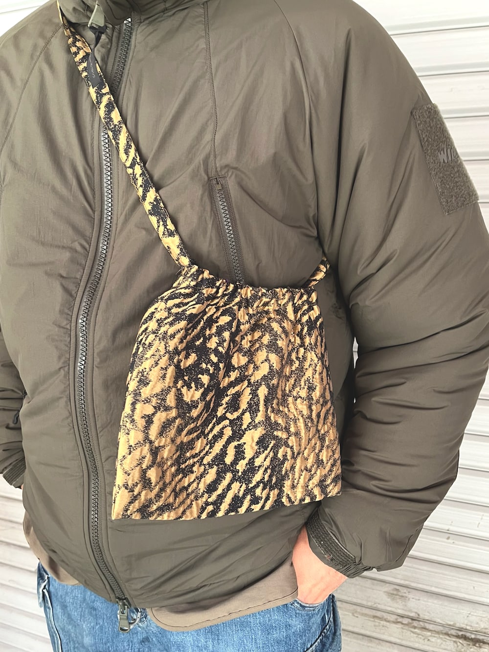 グリーン系のダウンジャケット/コート、ゴールド系のバッグ、ブルー系のキャップを着用したメンズの冬コーディネートの3枚目の写真