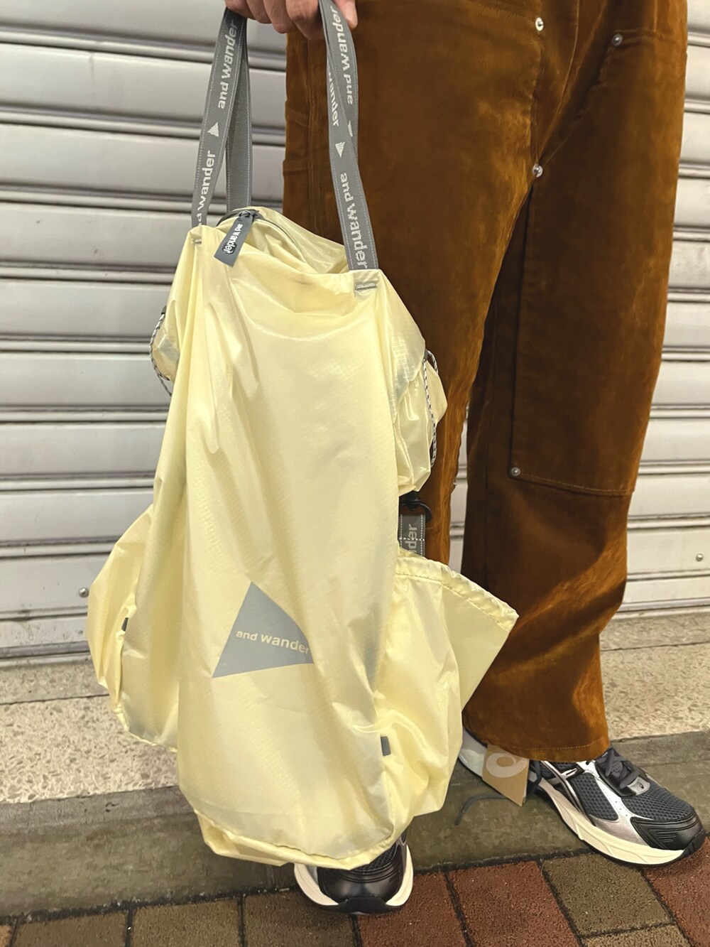 ブラウン系のデニムパンツ、ホワイト系のトートバッグ、ブラック系のTシャツ/カットソーを着用したメンズの秋コーディネートの3枚目の写真