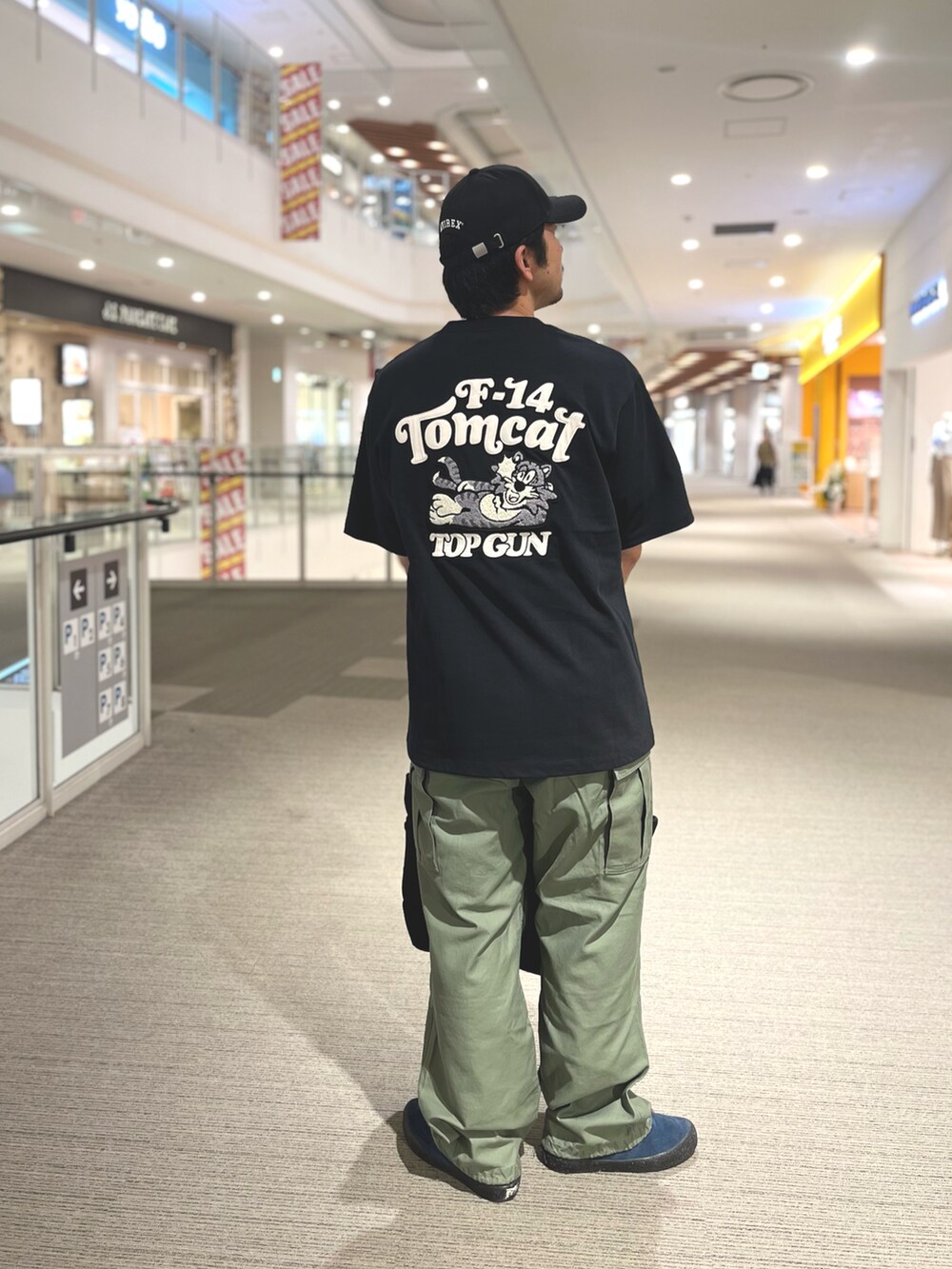 ブラック系のトートバッグ、ブラック系のTシャツ/カットソー、グリーン系のカーゴパンツを着用したメンズの夏コーディネートの2枚目の写真