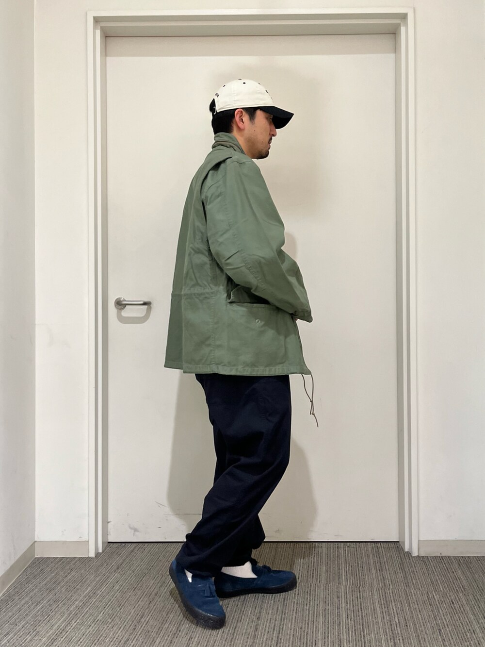 ブルー系のその他パンツ、グリーン系のミリタリージャケット、ホワイト系のキャップを着用したメンズの春コーディネートの2枚目の写真