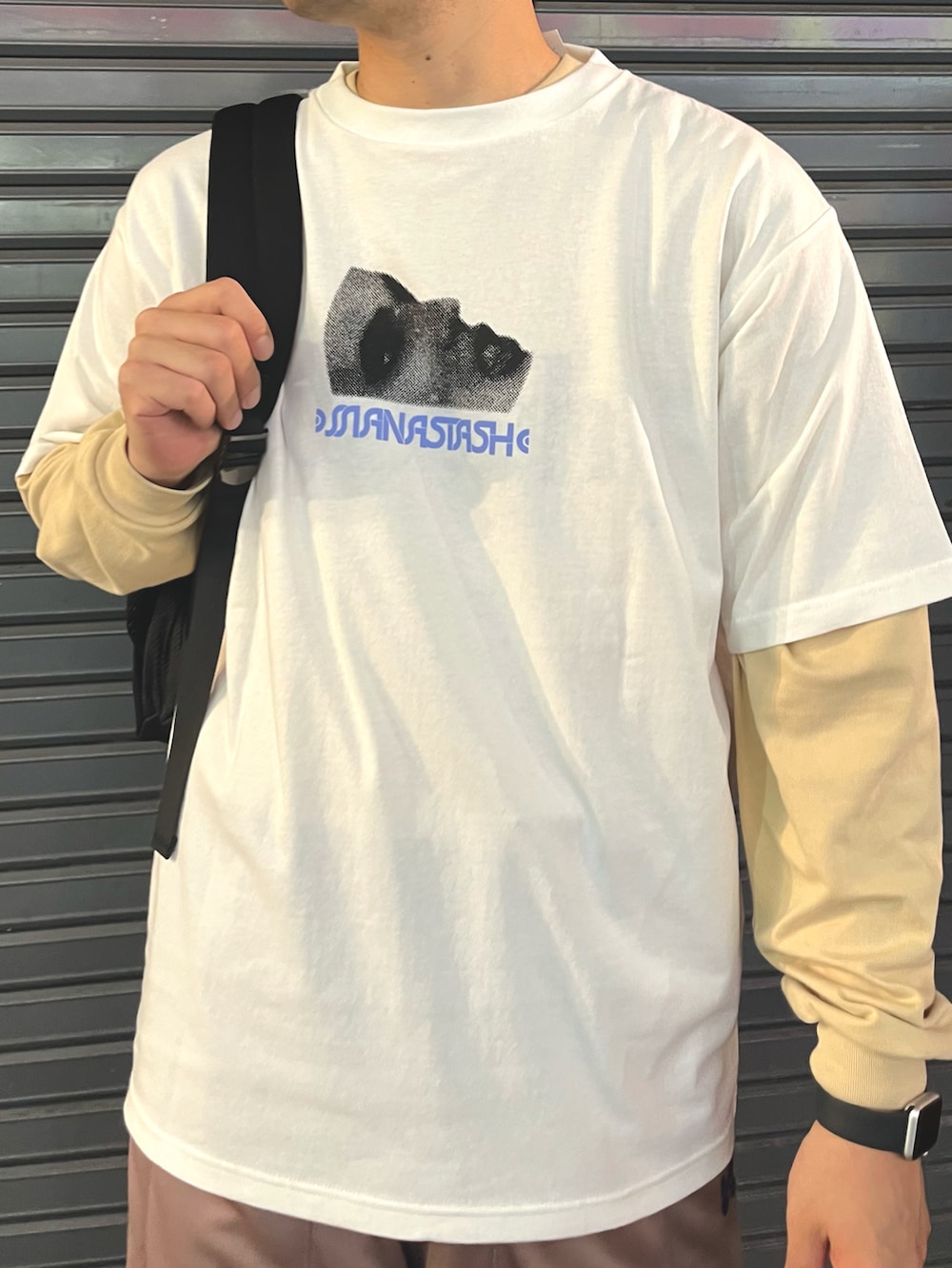 ホワイト系のTシャツ/カットソー、ベージュ系のパンツ、ブラック系のバックパック/リュックを着用したメンズの夏コーディネートの2枚目の写真